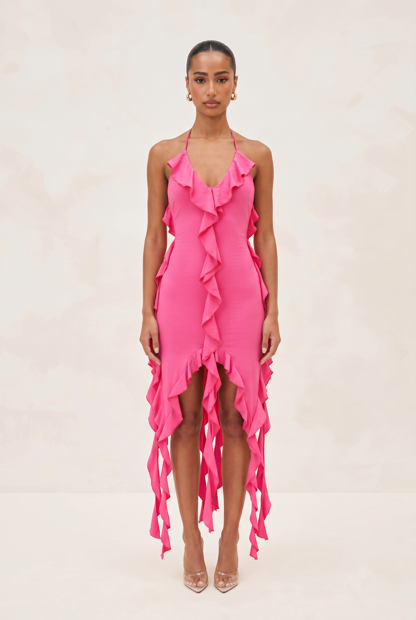 Woman wearing a bright pink ruffled dress on a beige background