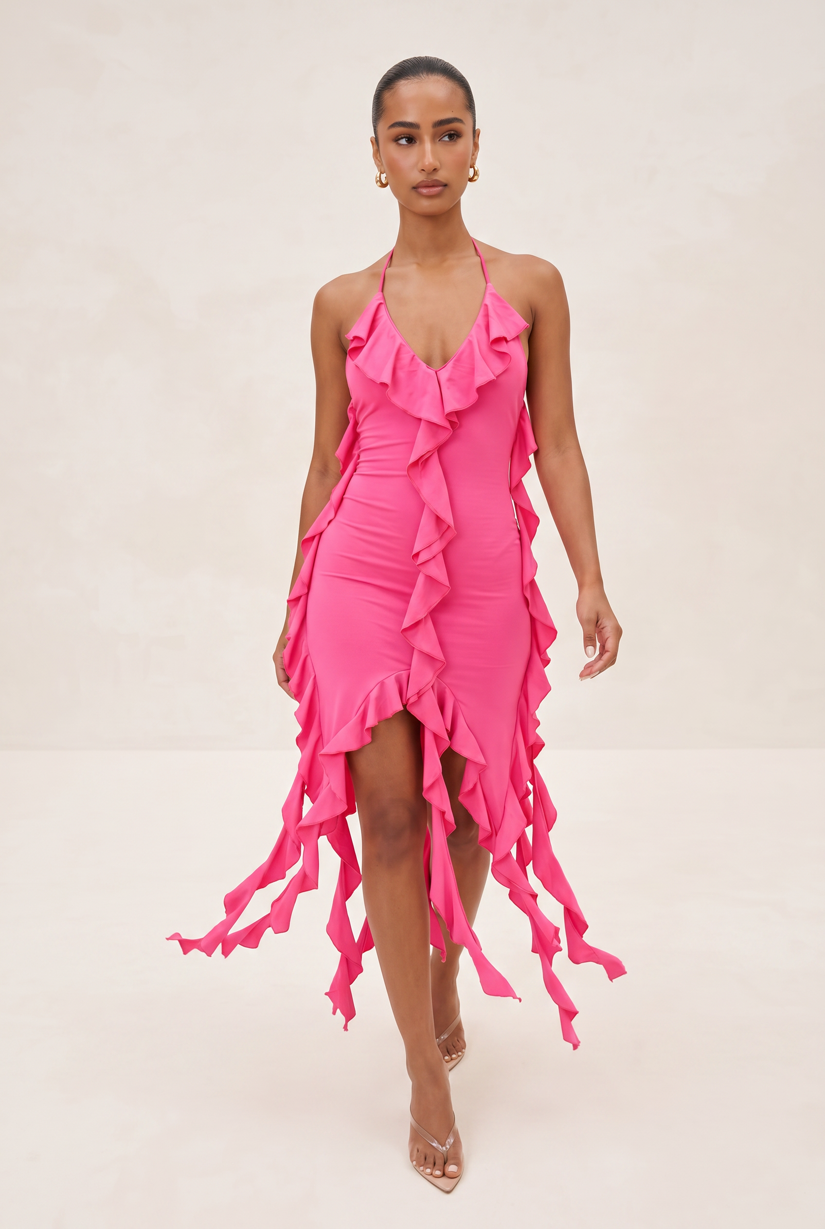 Woman wearing a bright pink dress with ruffled details on a white background