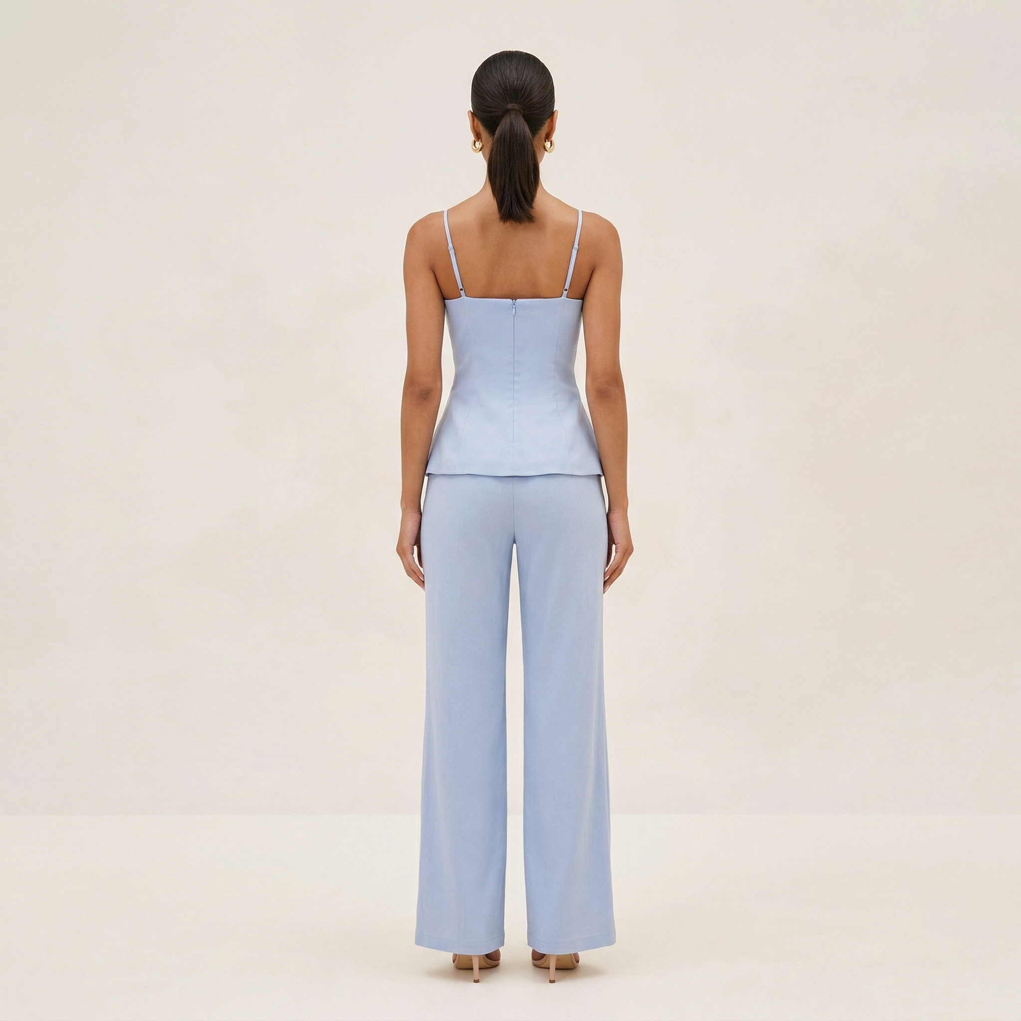 Woman wearing a light blue jumpsuit on a beige background