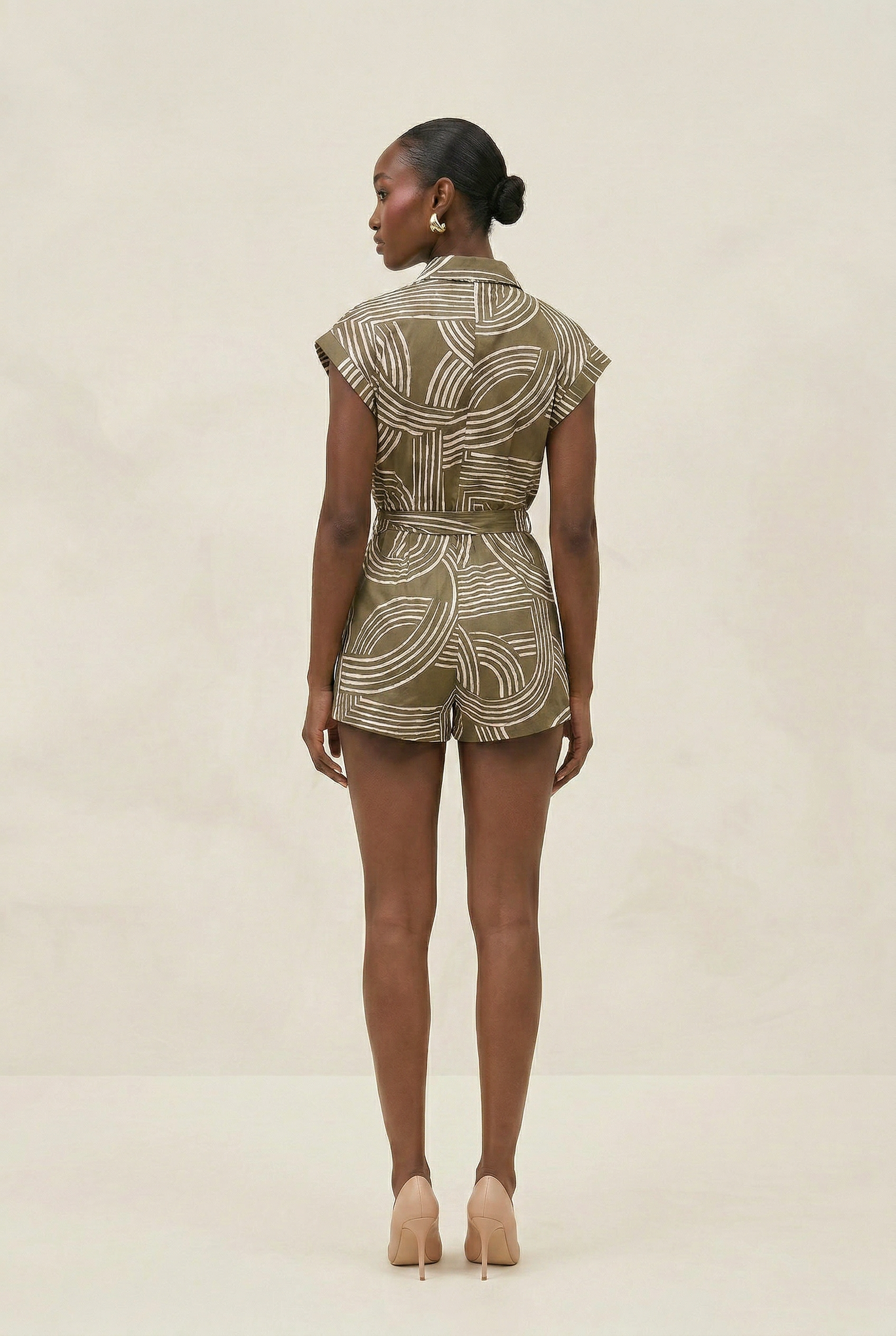 Woman wearing a patterned romper on a beige background