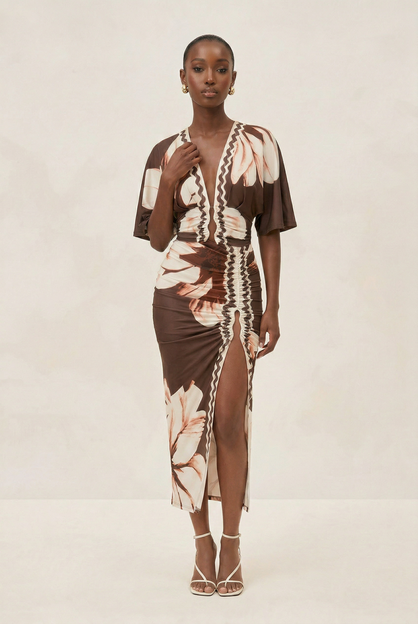 Woman wearing a floral dress with a brown base on a plain background