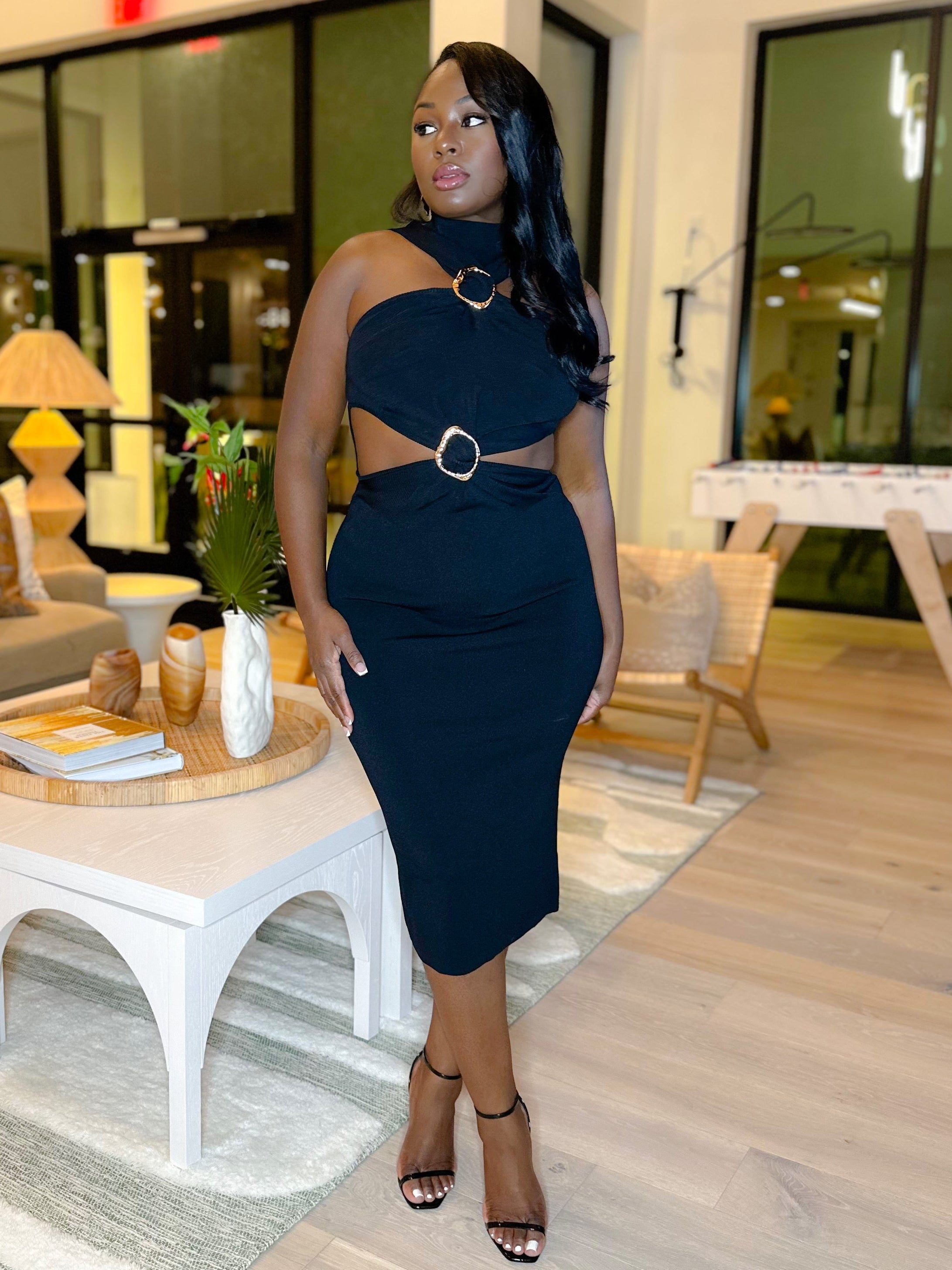 Woman in a black dress standing in a modern living room.