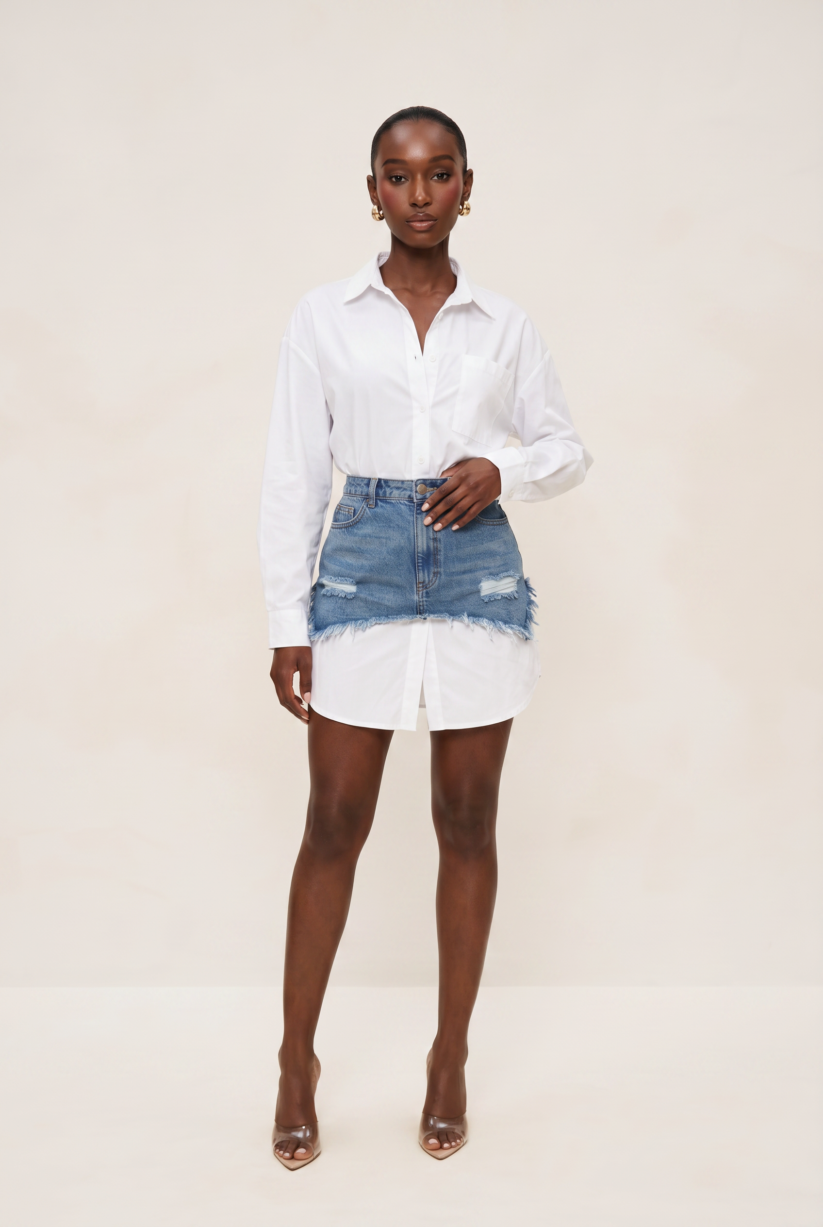 Woman wearing a white shirt and denim skirt on a plain background