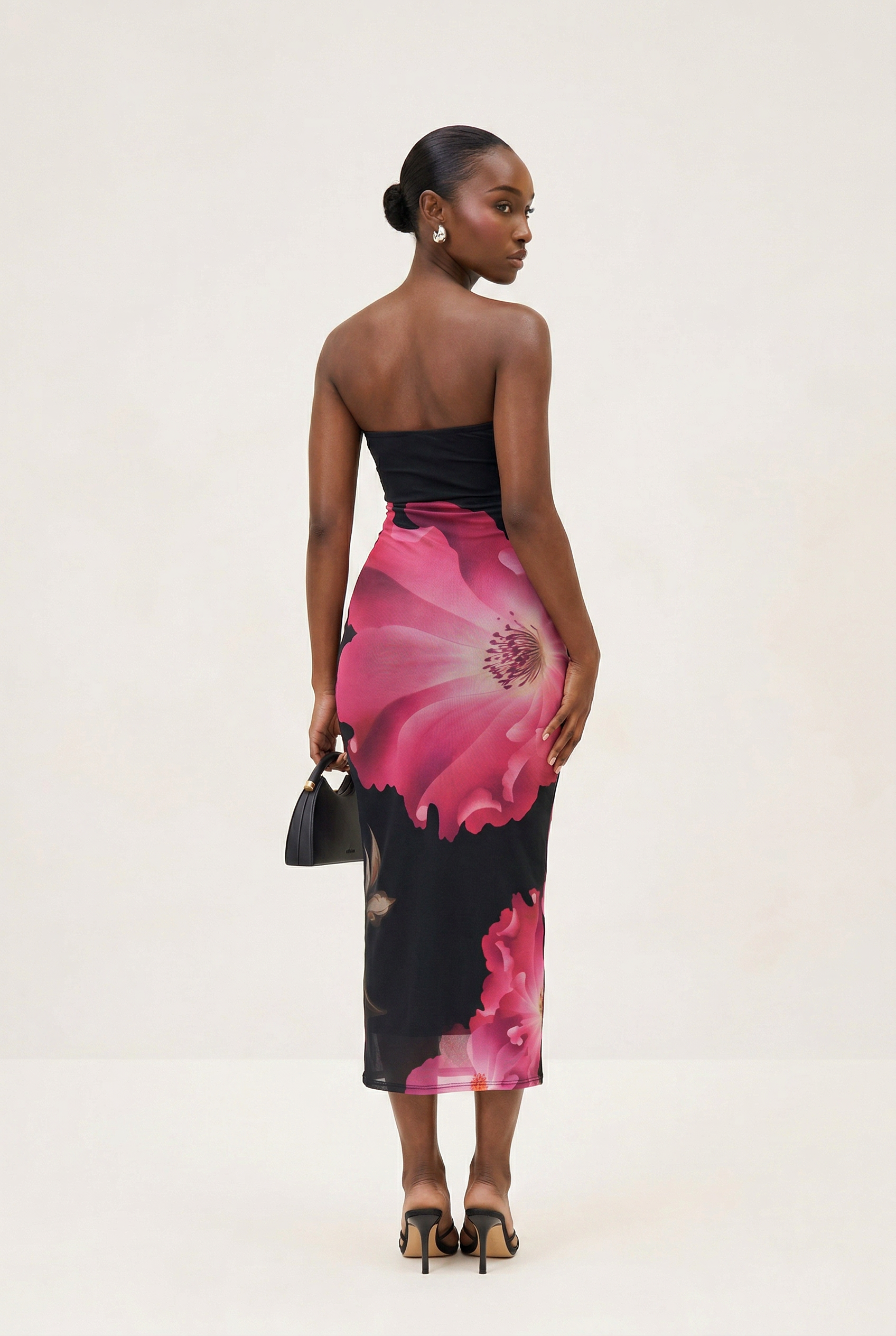 Woman wearing a strapless dress with pink floral design on a white background