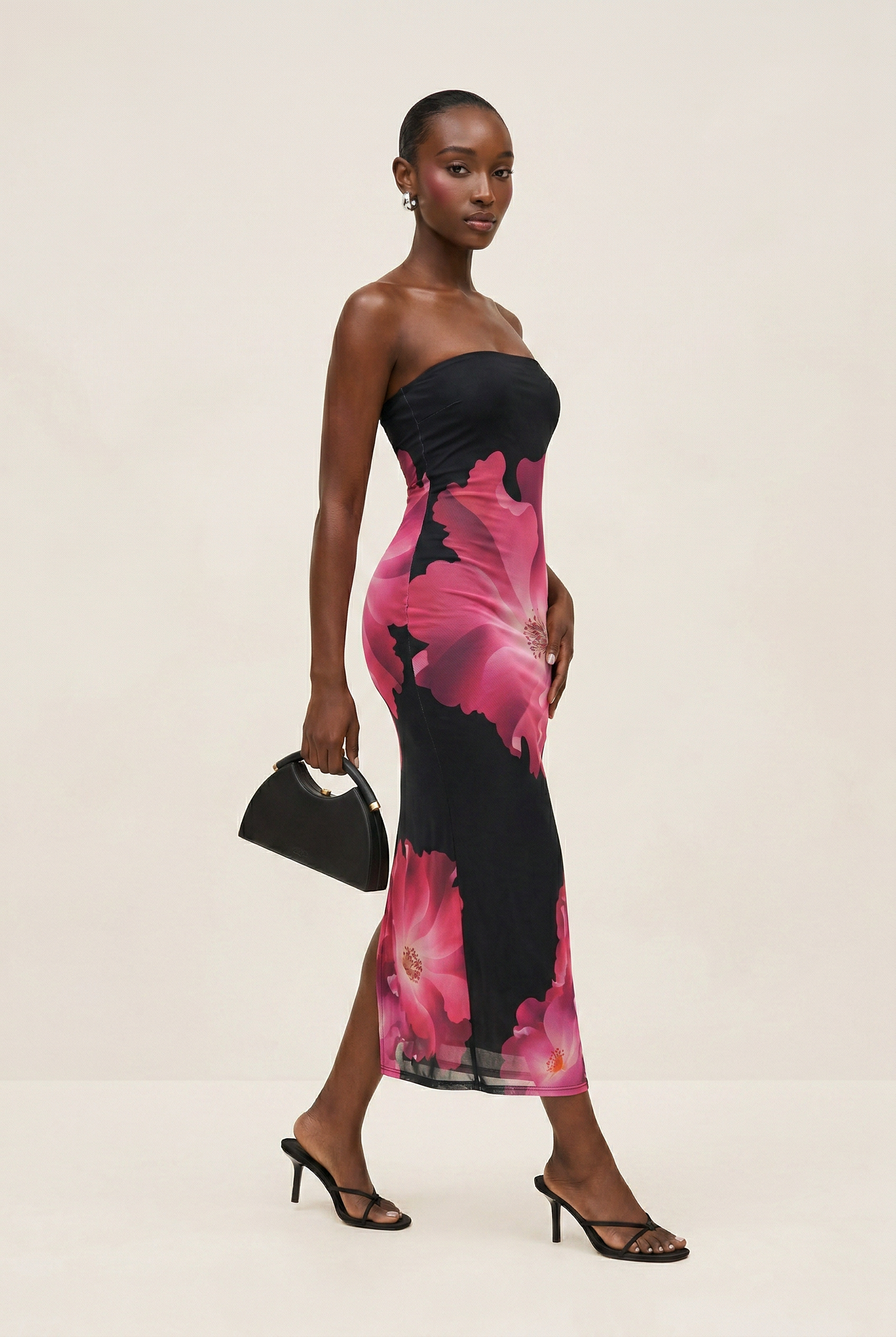Woman wearing a strapless black and pink floral dress on a beige background
