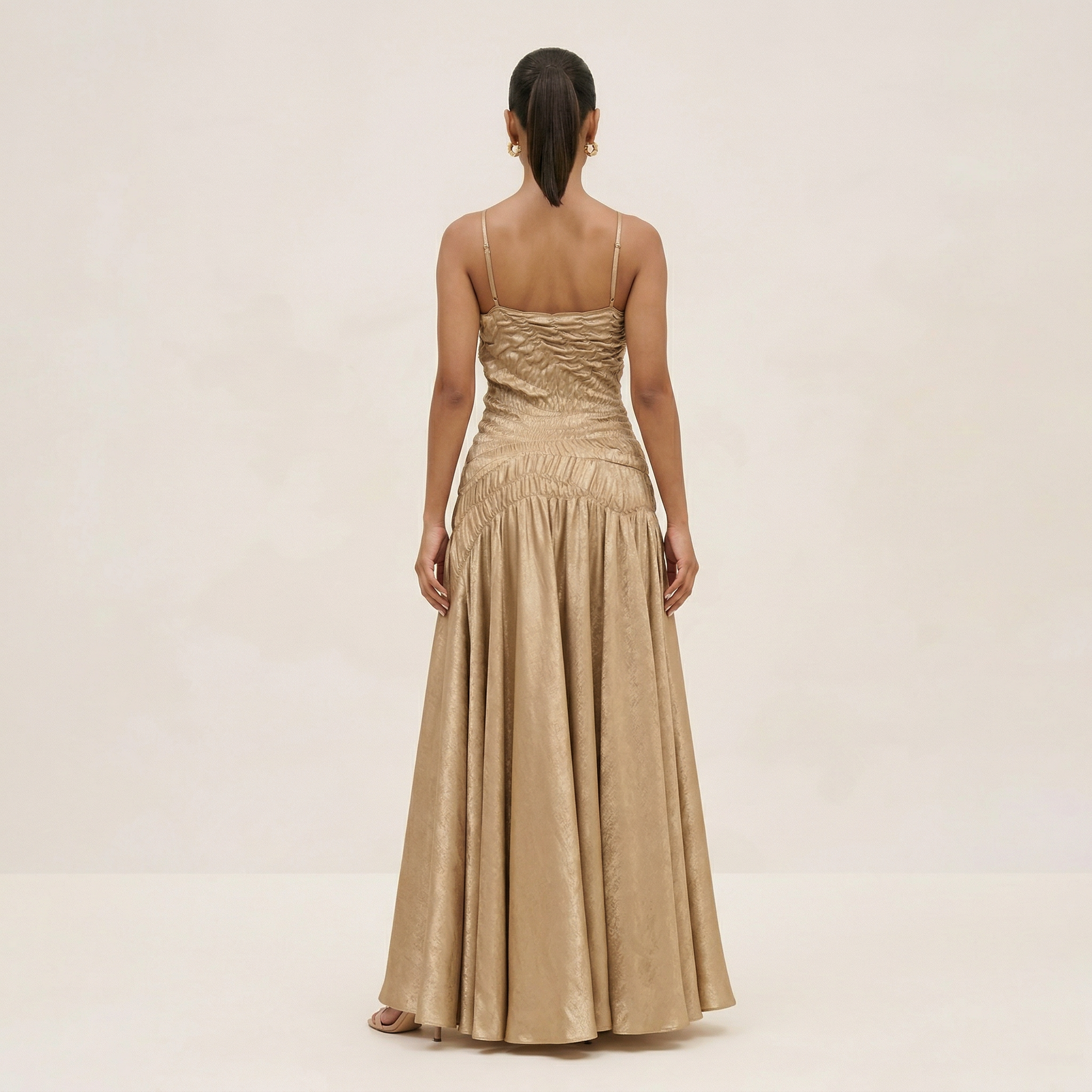 Woman wearing a beige evening gown on a plain background