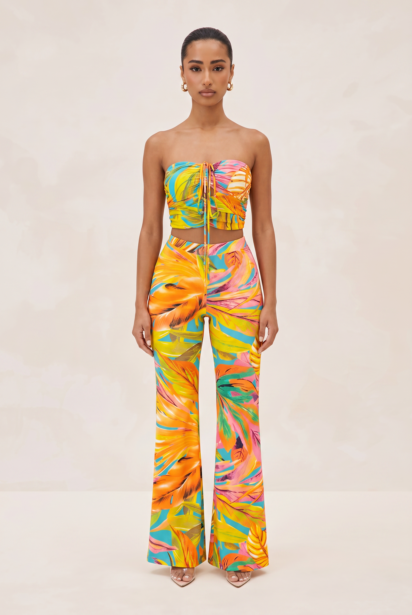 Woman wearing a colorful strapless top and pants set on a beige background