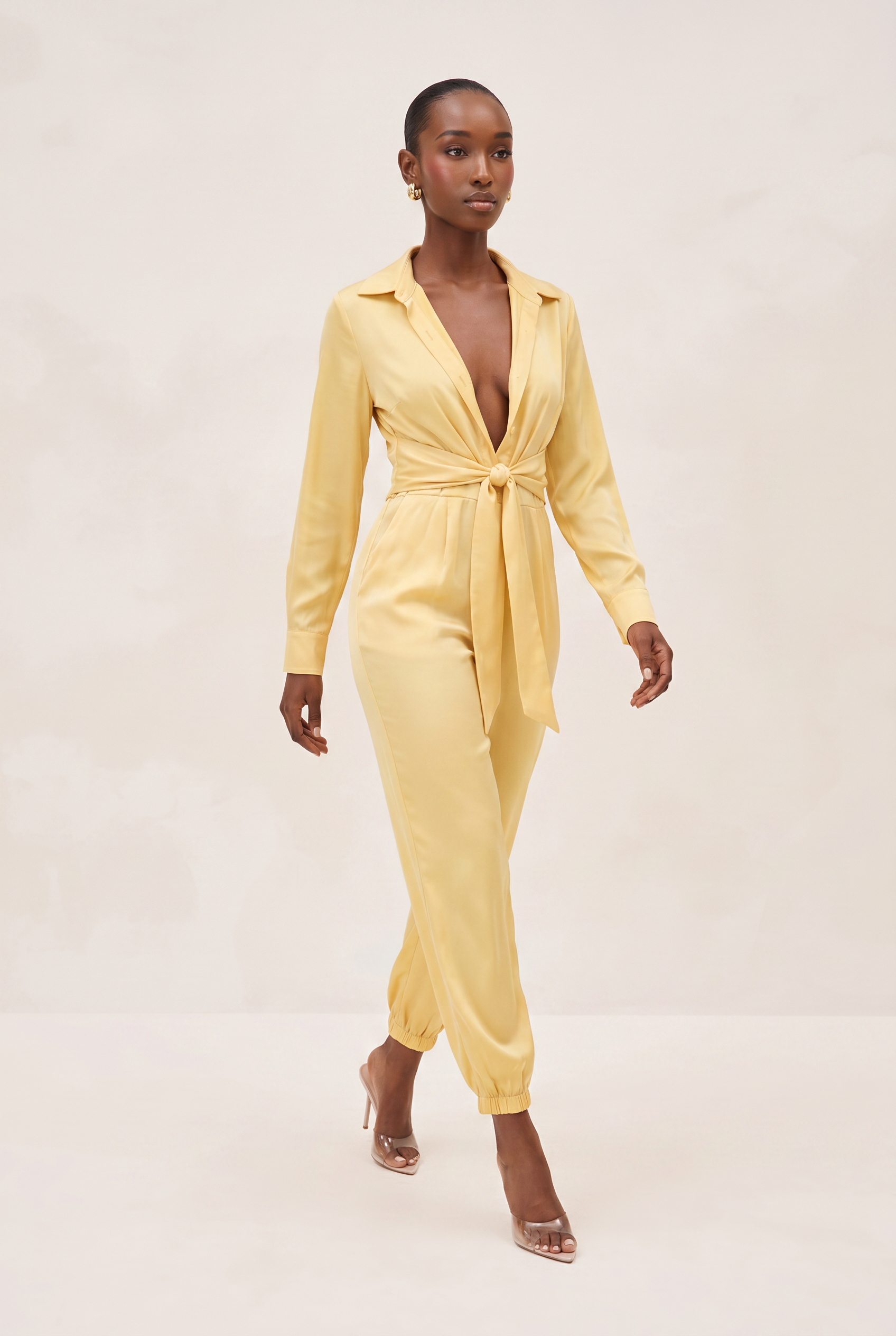 Woman wearing a yellow jumpsuit on a plain background