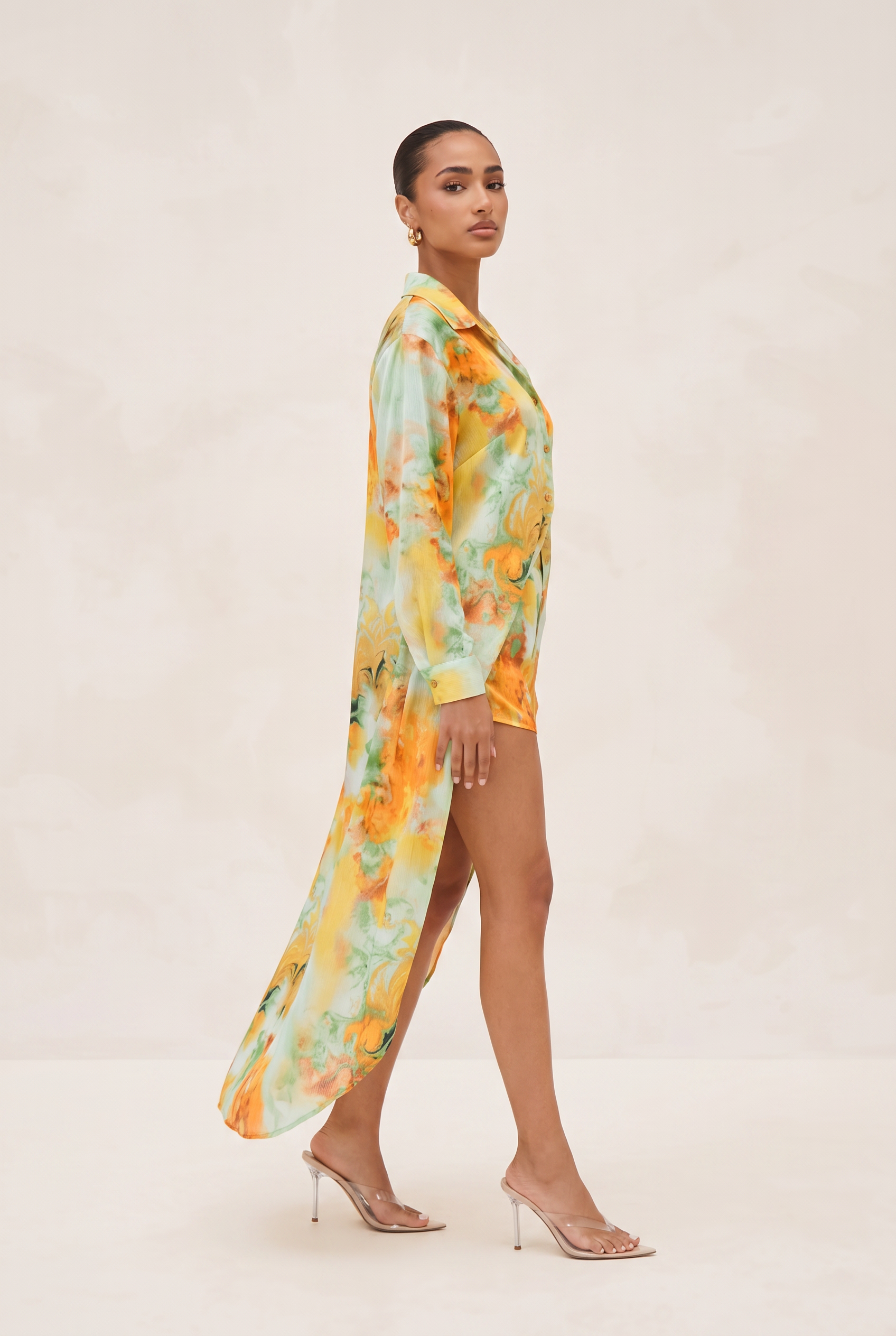 Woman wearing a colorful floral dress on a plain background