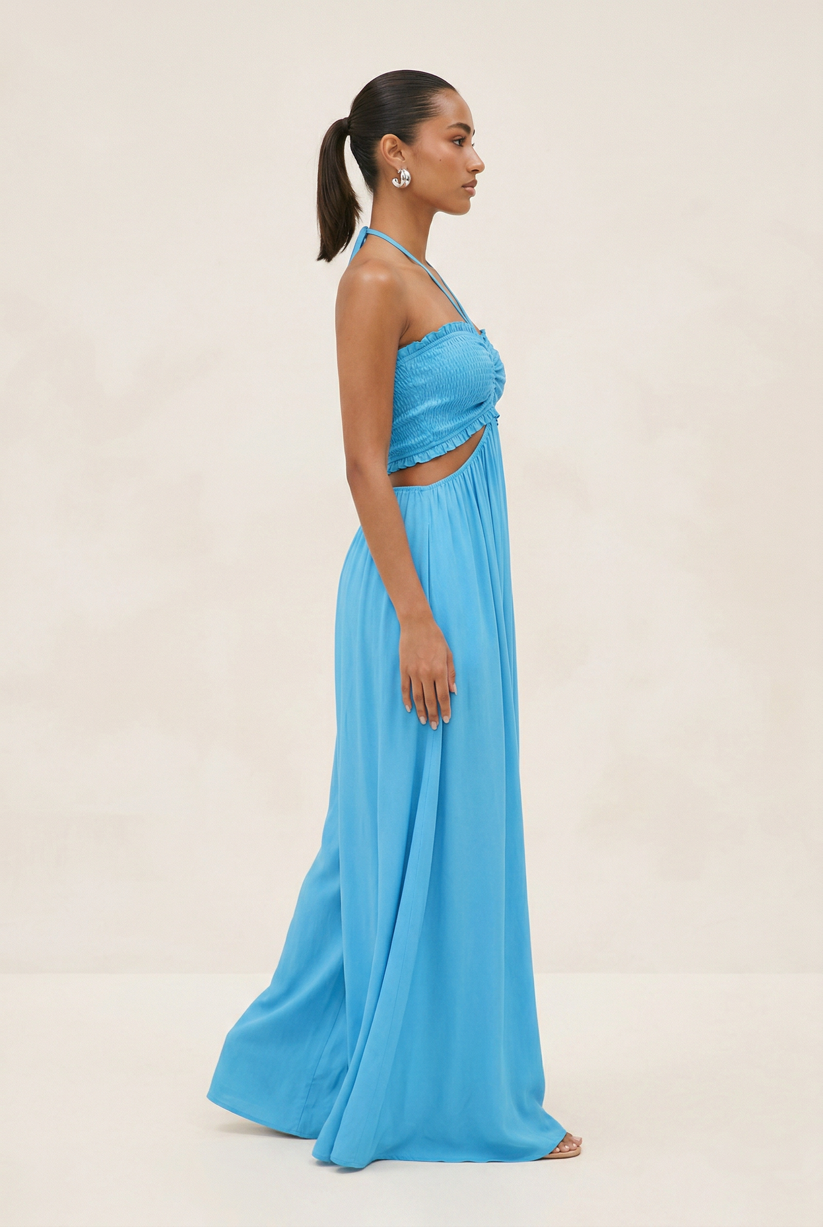Woman wearing a blue two-piece dress against a beige background