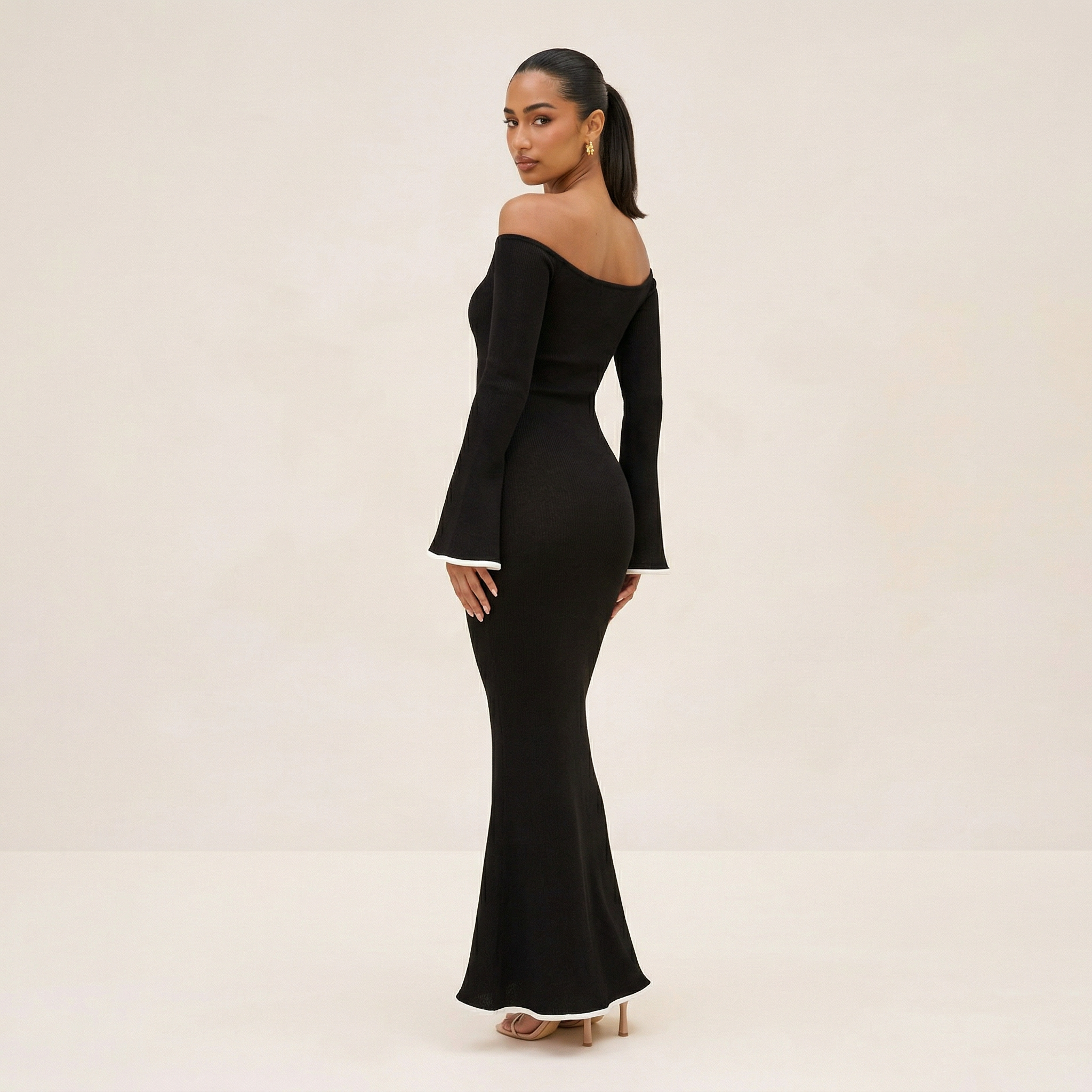 Woman wearing a black off-shoulder long-sleeve gown on a beige background