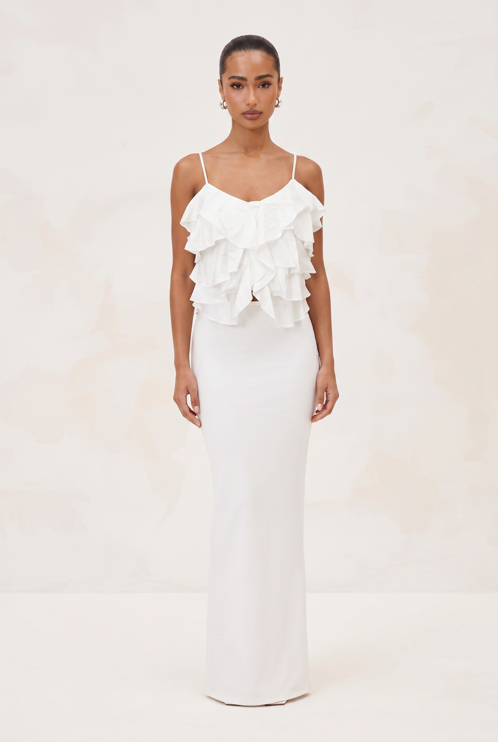 Woman wearing a white ruffled dress against a plain background
