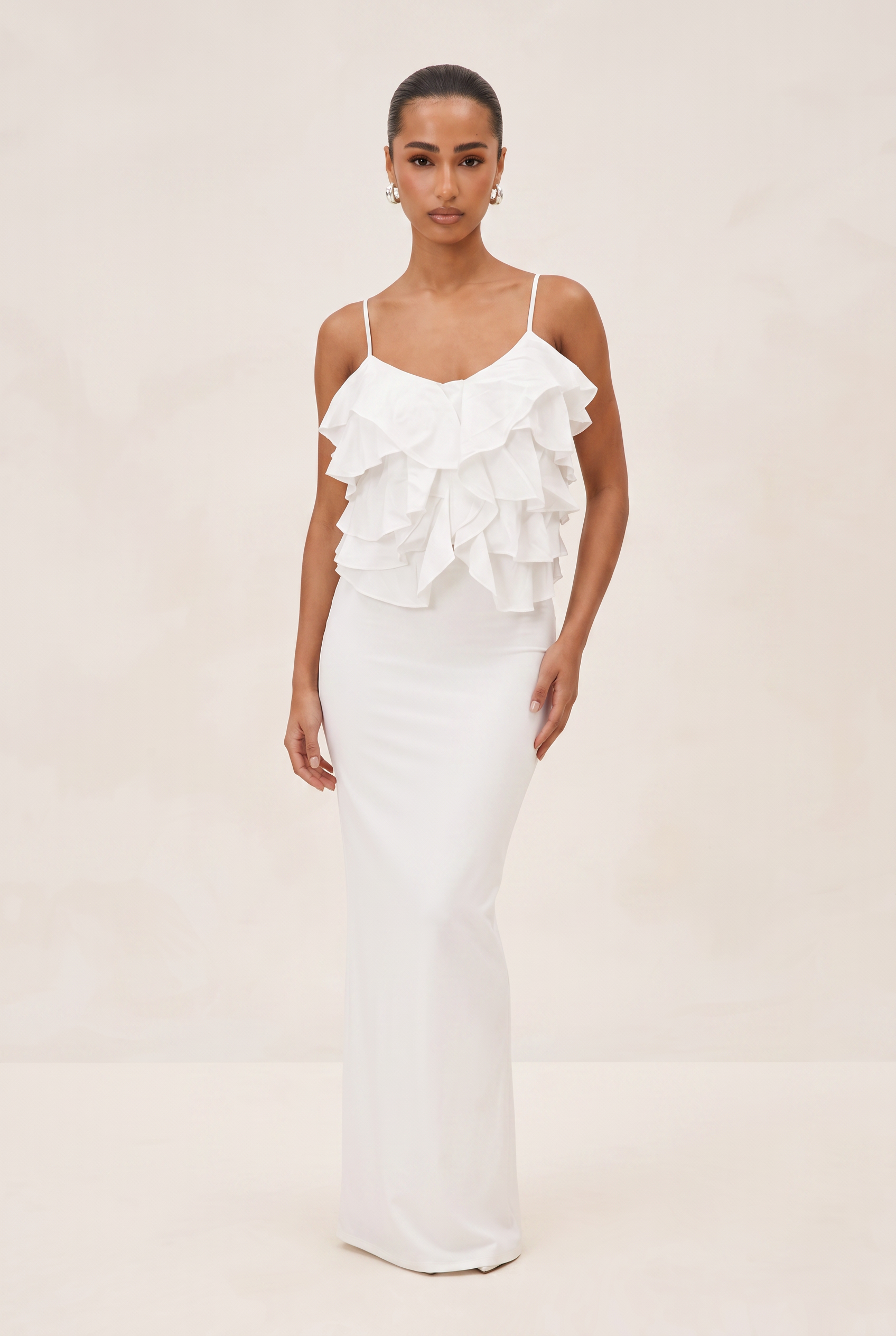 Woman wearing a white ruffled dress on a plain background