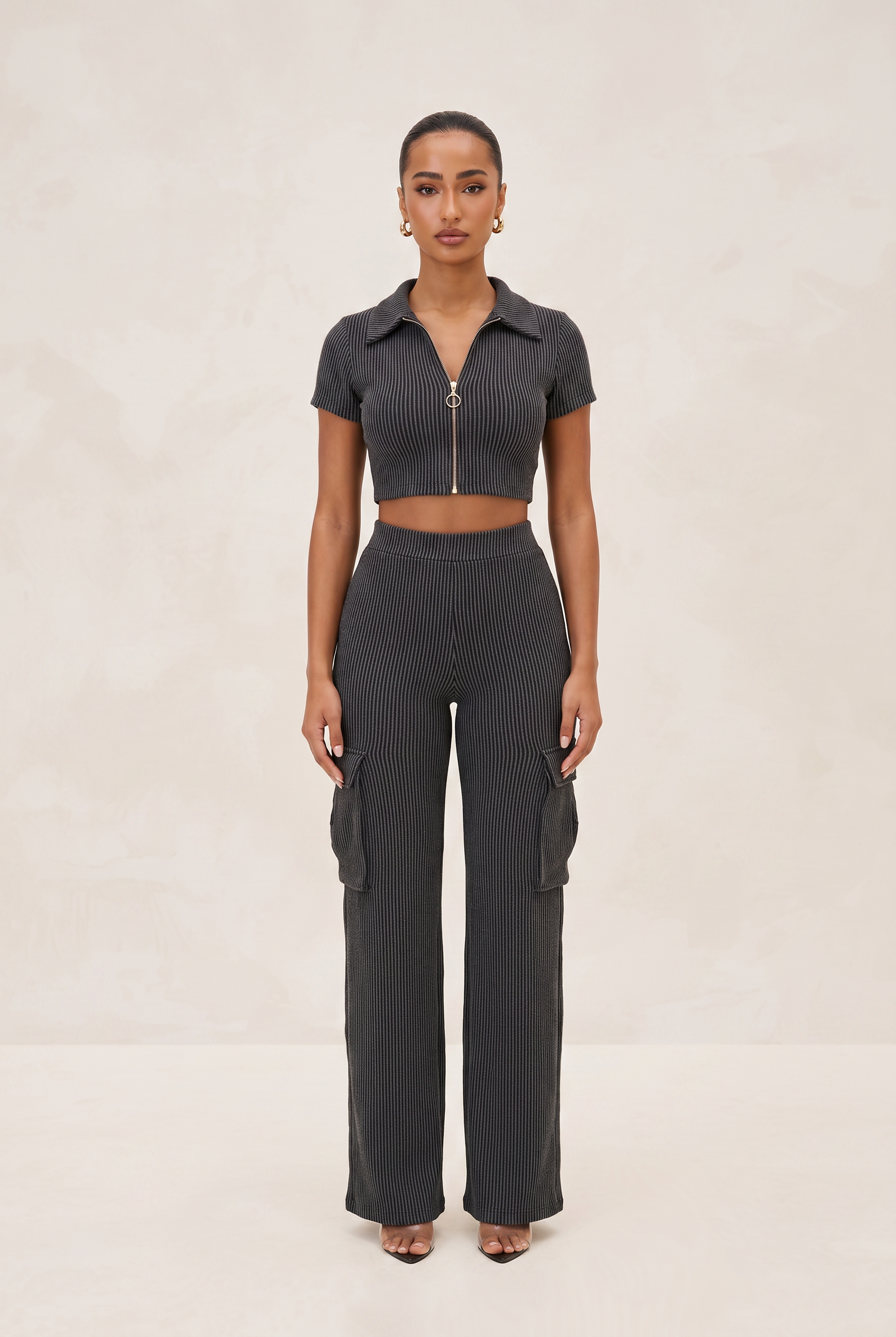 Woman wearing a dark ribbed knit outfit with a matching top and cargo pants on a beige background