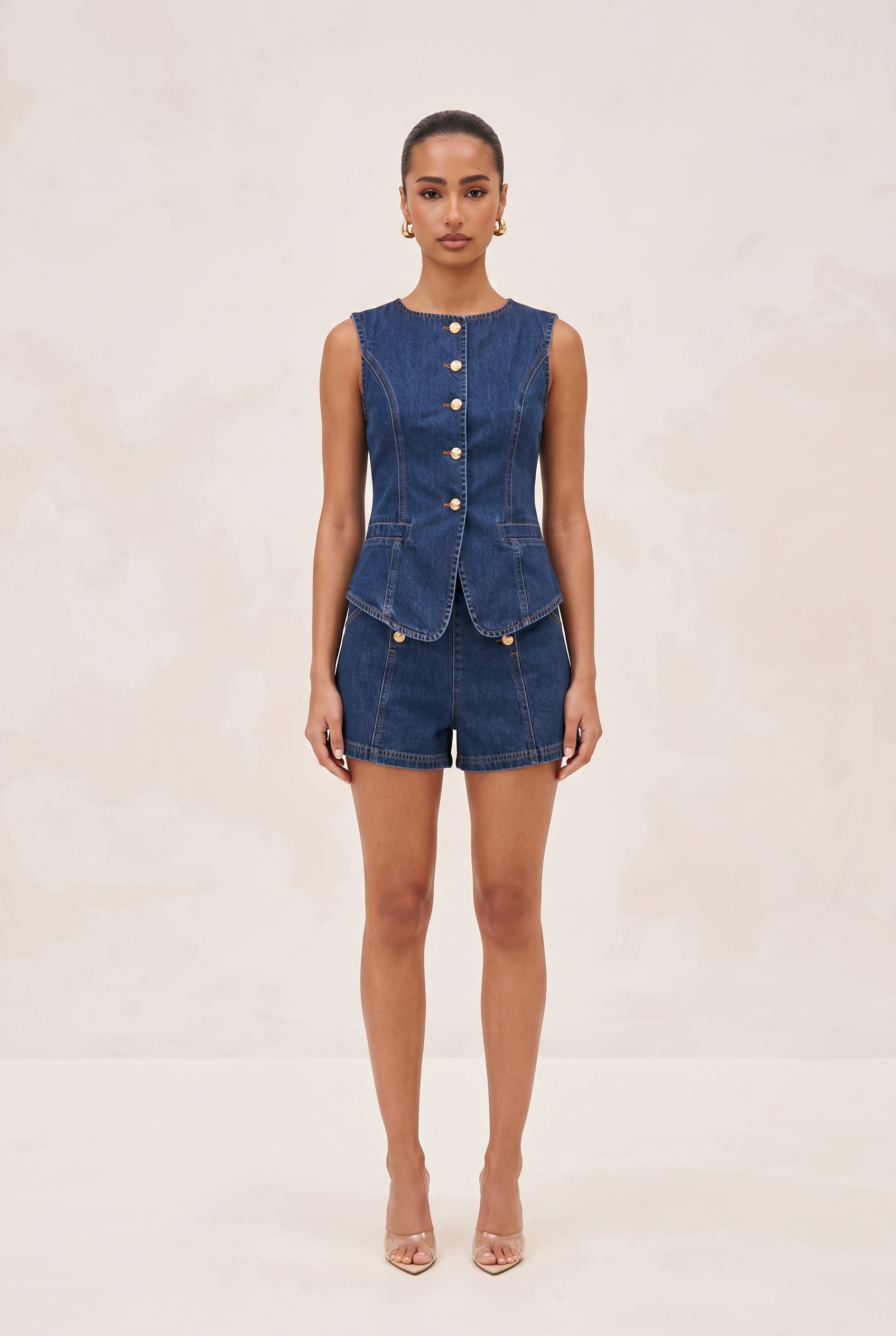 Woman wearing a denim vest and shorts on a beige background