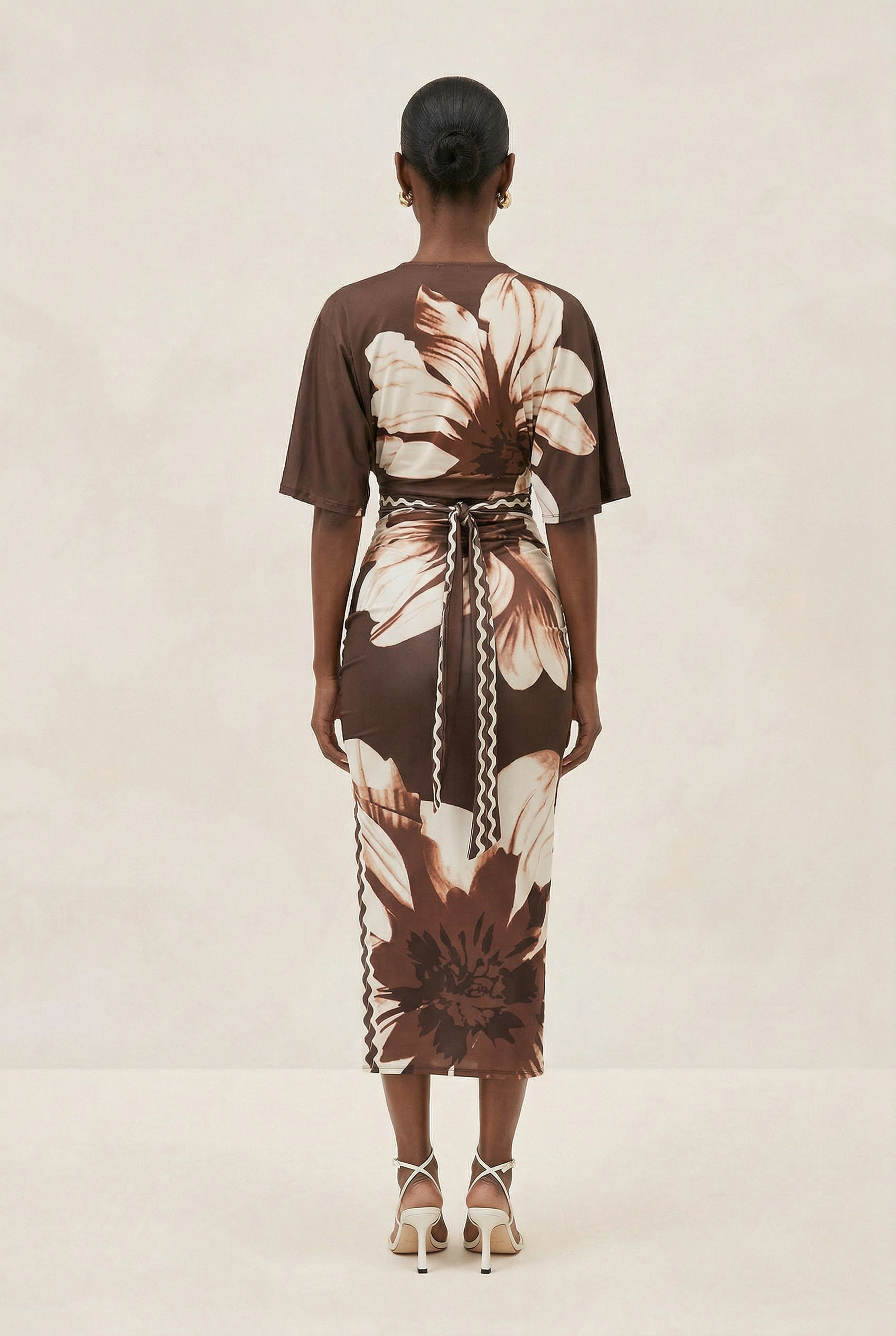 Woman wearing a brown floral dress on a beige background