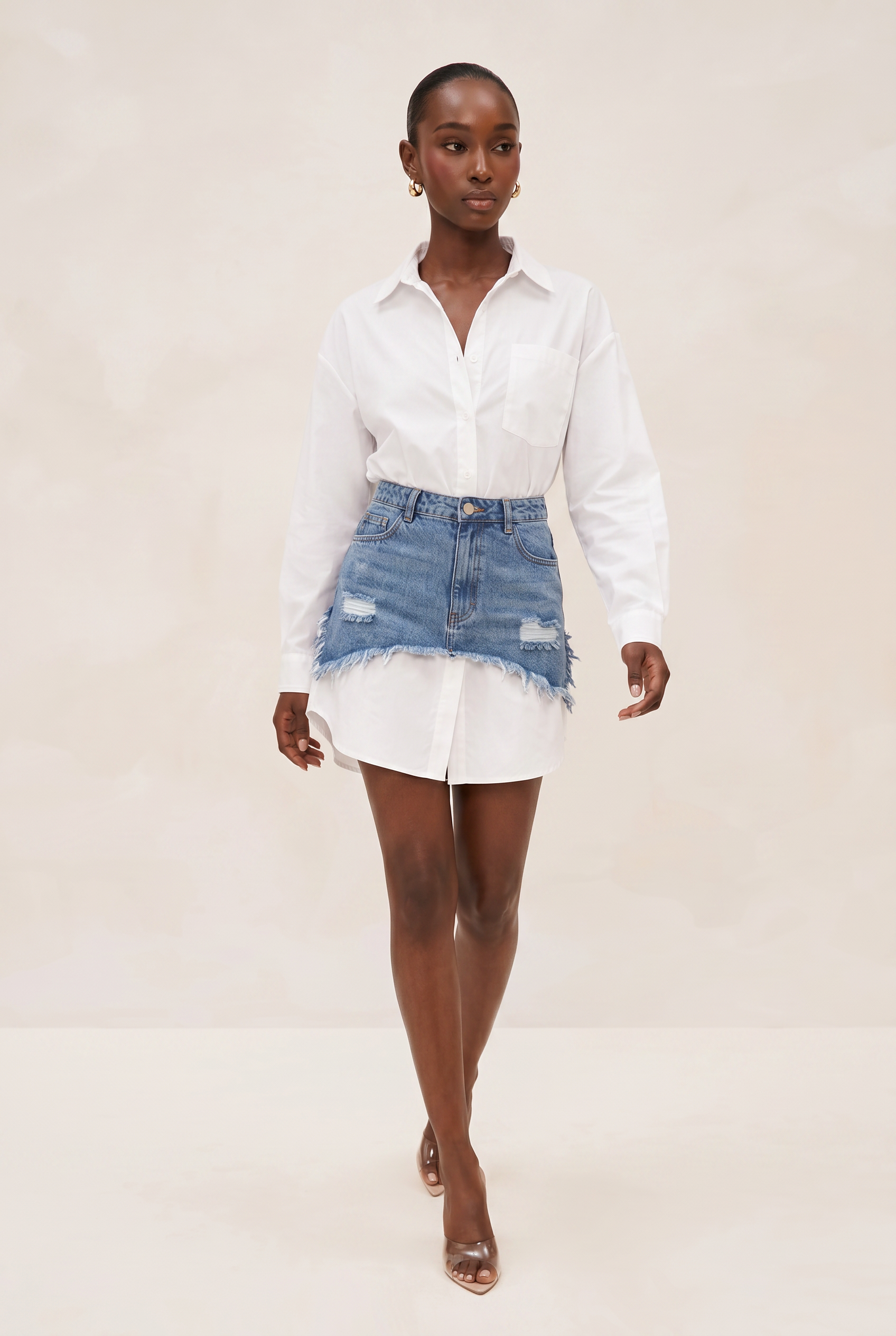 Woman wearing a white shirt and denim skirt on a beige background