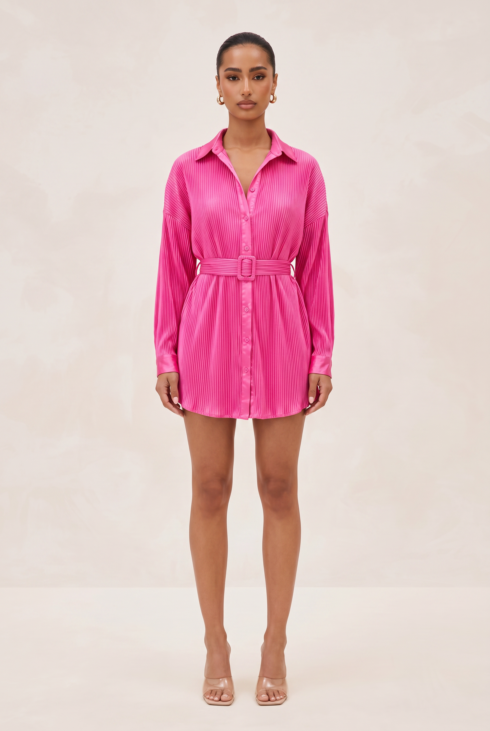 Woman wearing a bright pink shirt dress on a beige background