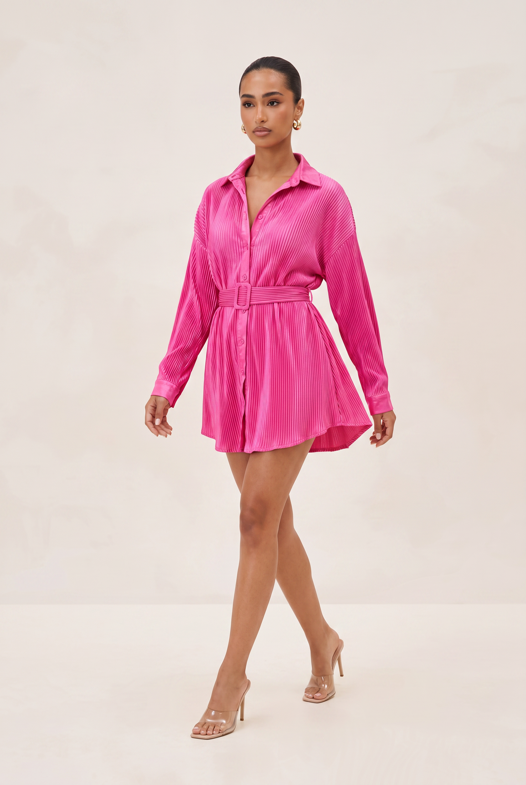 Woman wearing a bright pink shirt dress on a white background