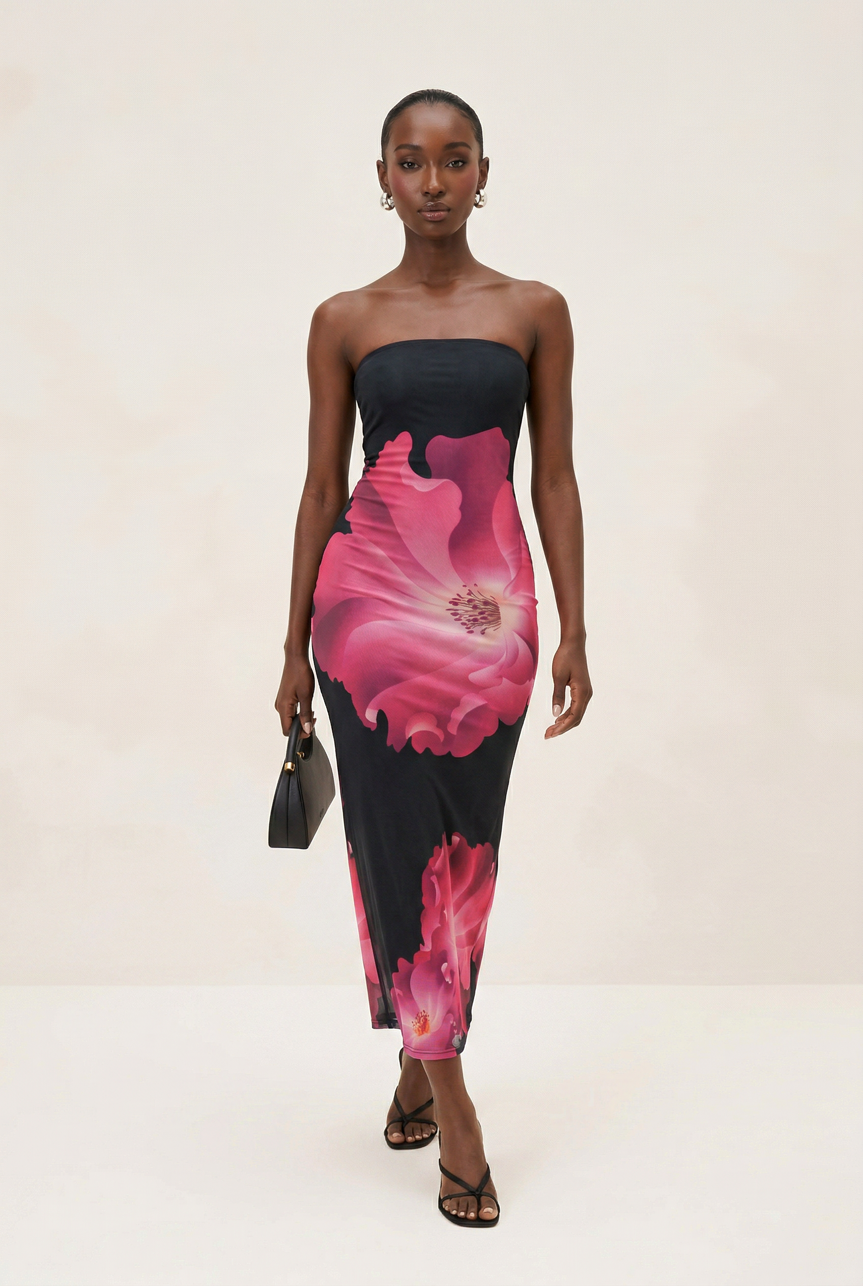 Woman wearing a strapless dress with pink floral design on a plain background