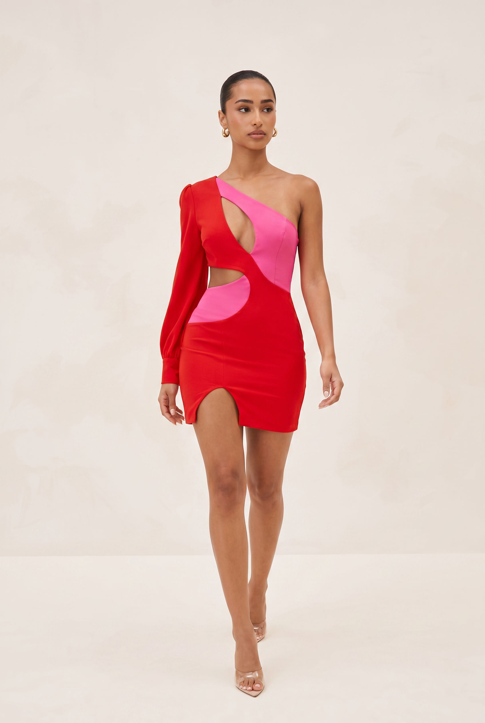 Woman wearing a red and pink one-shoulder dress on a beige background