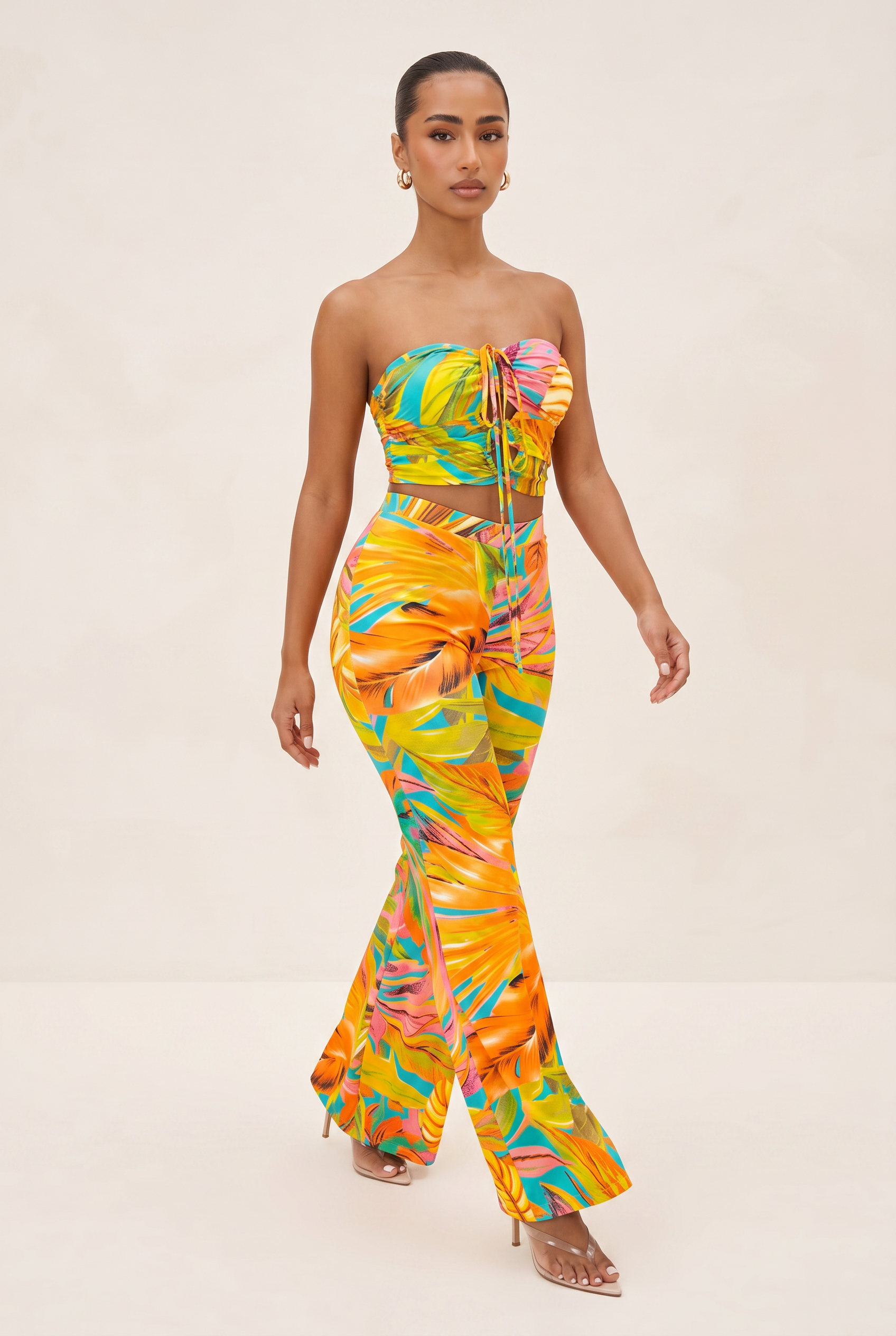 Woman wearing a colorful strapless jumpsuit with leaf patterns on a beige background