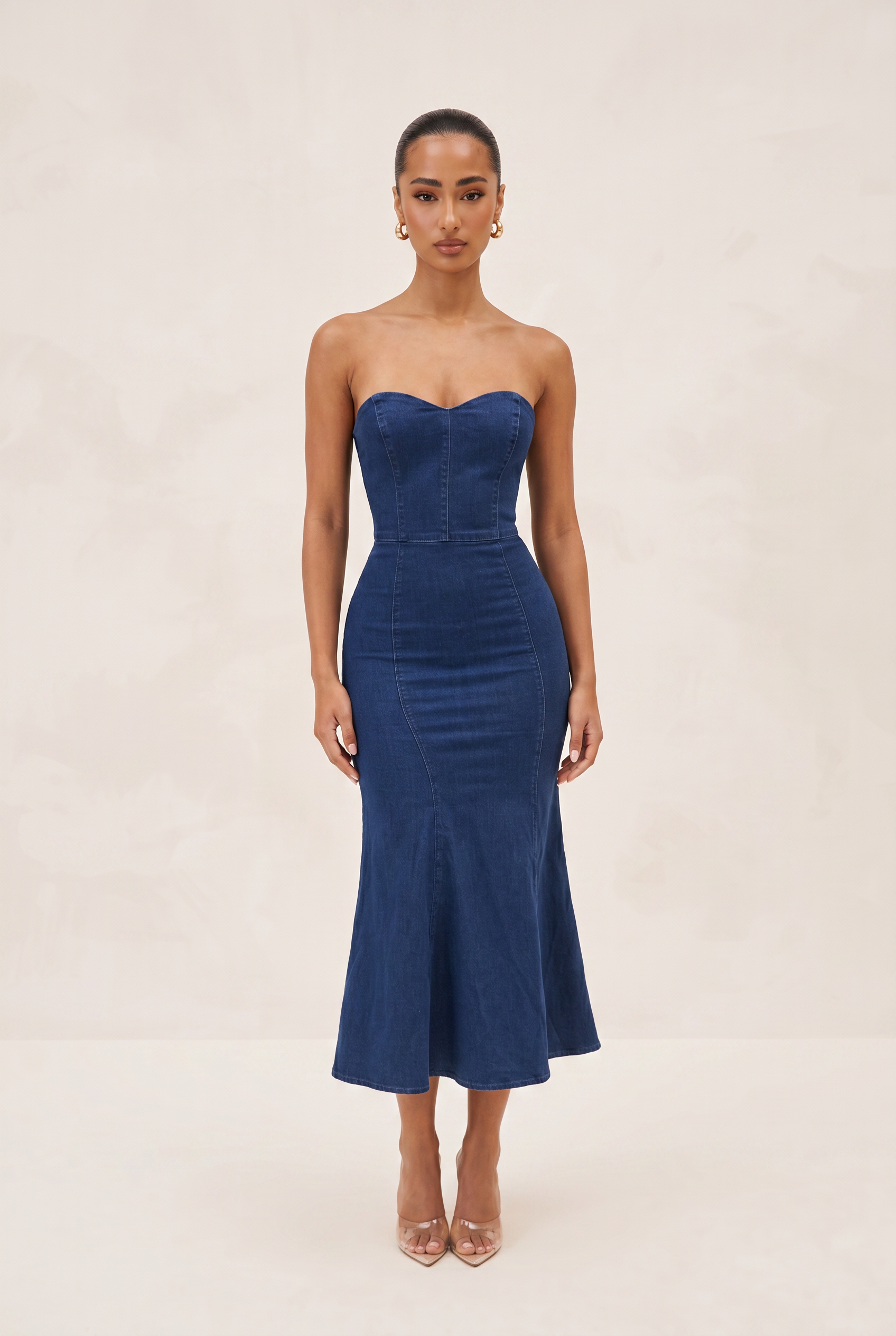 Woman wearing a strapless blue dress against a beige background