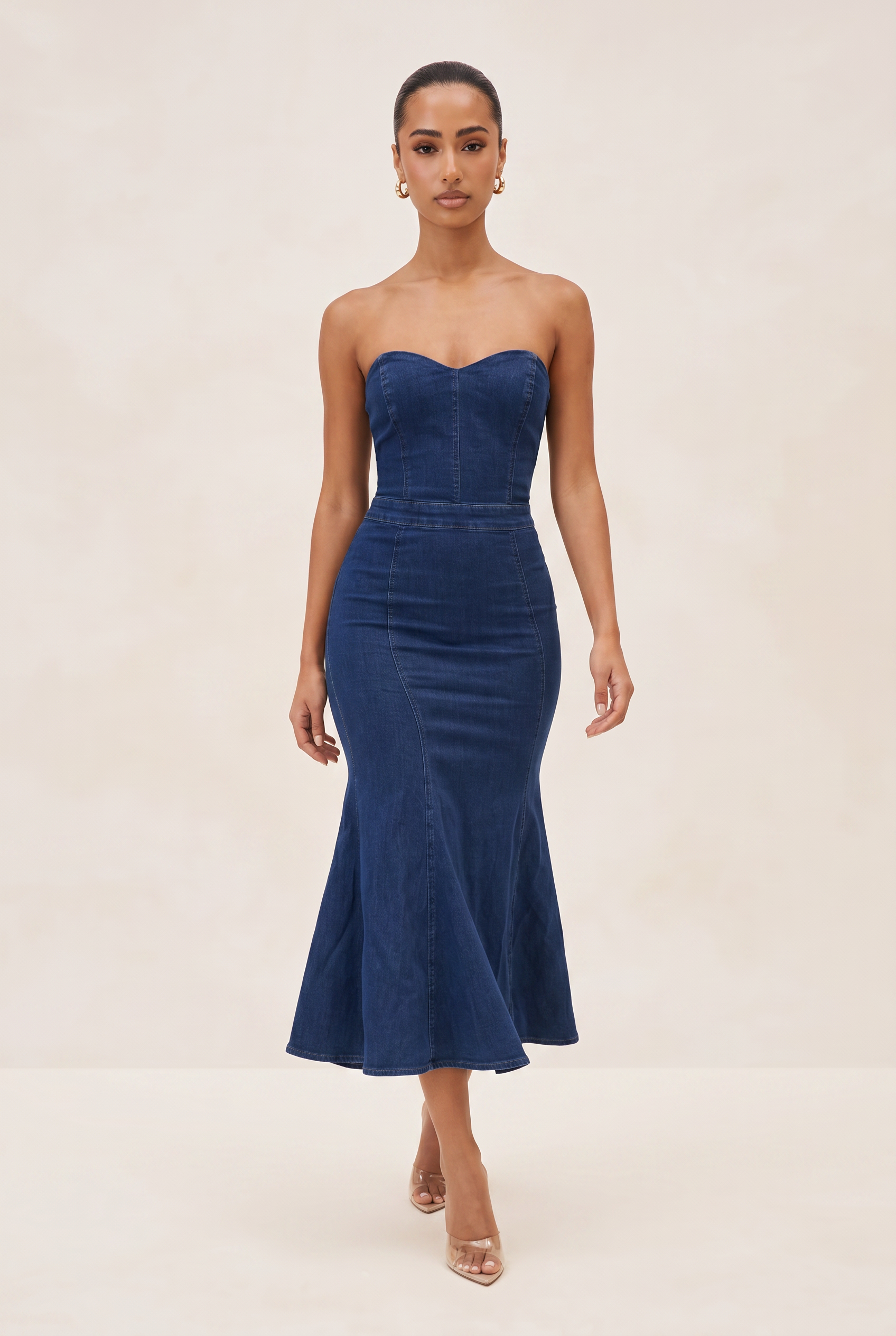 Woman wearing a strapless navy dress on a beige background