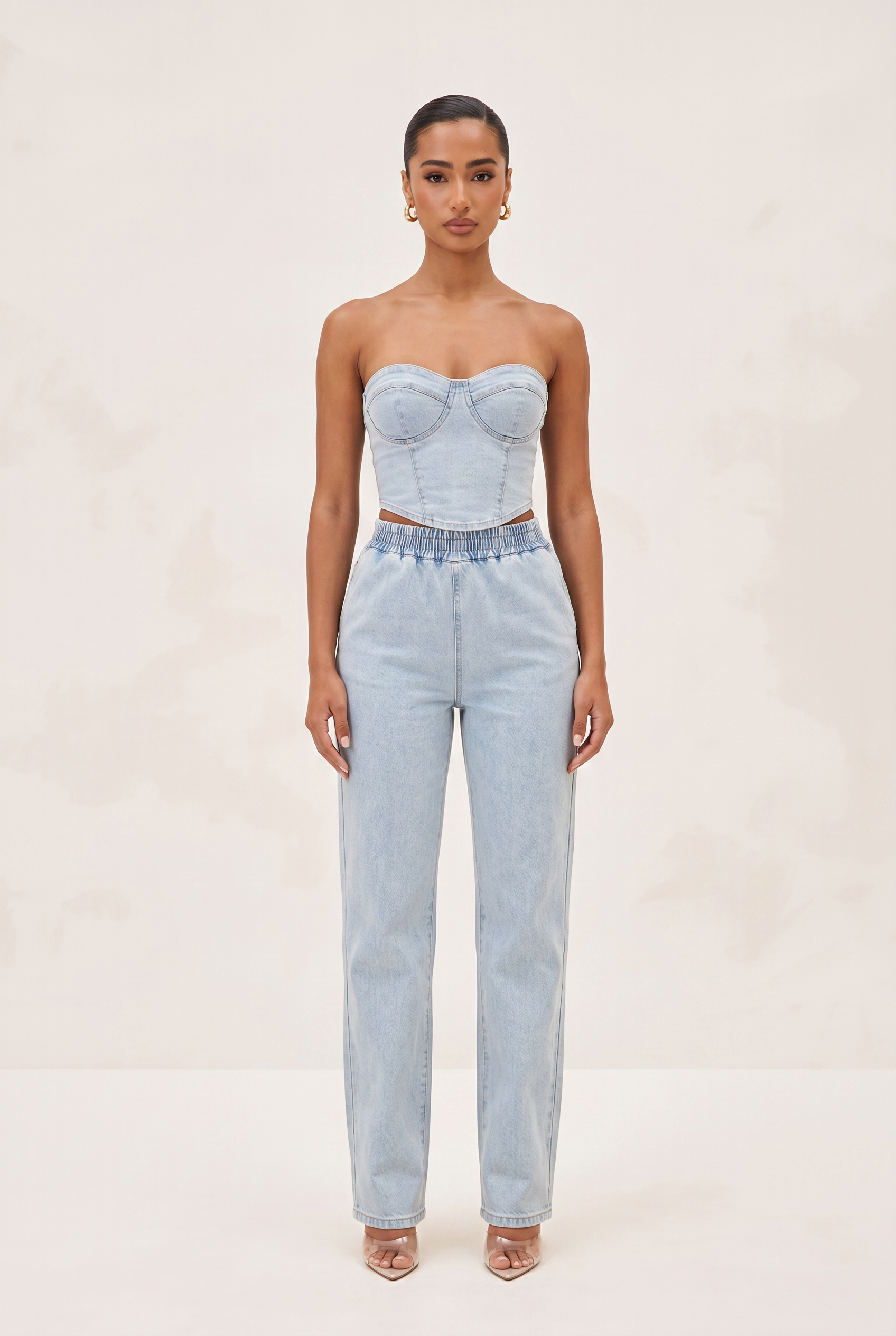 Woman wearing a light blue strapless top and high-waisted jeans on a white background
