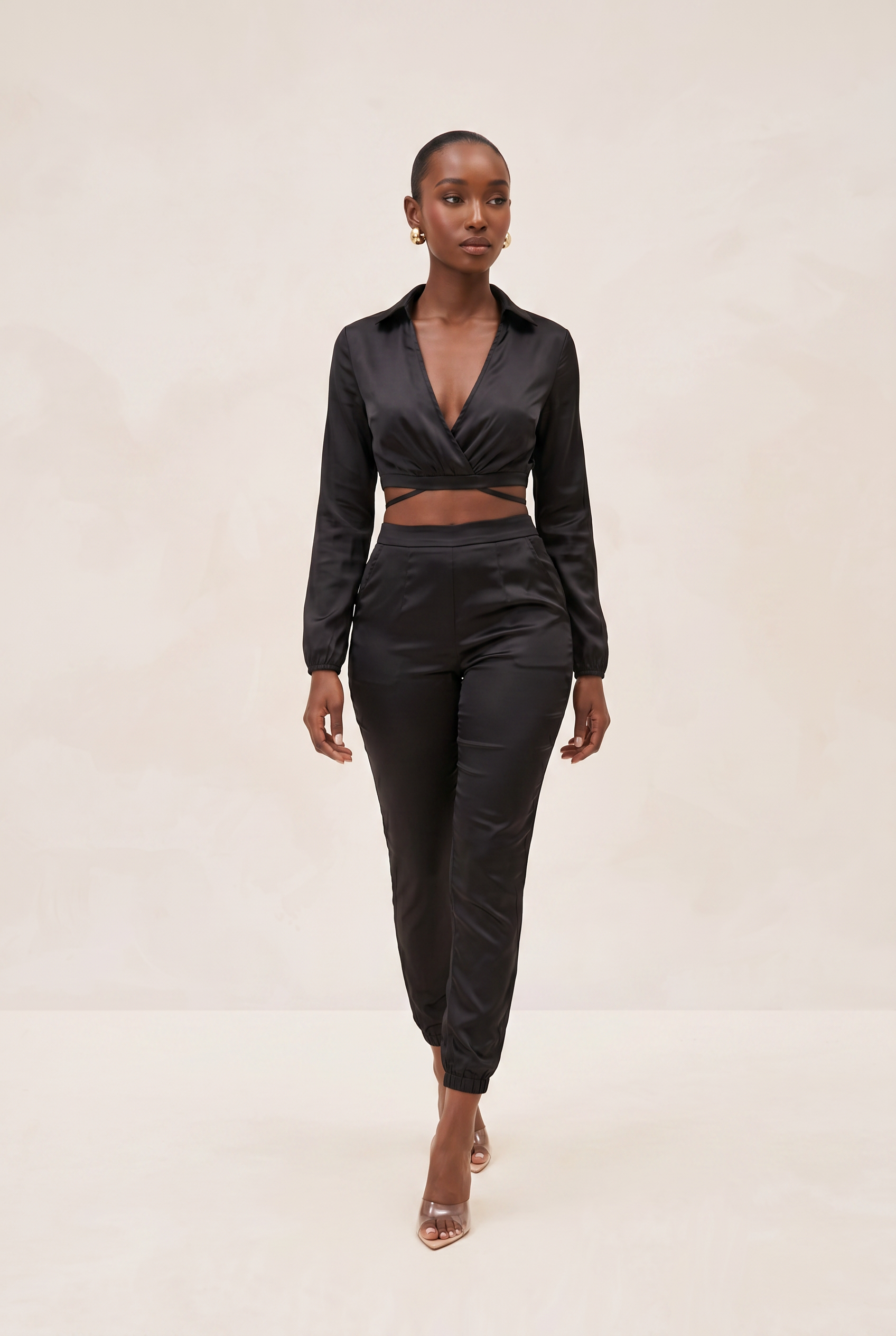 Woman wearing a black satin outfit on a beige background