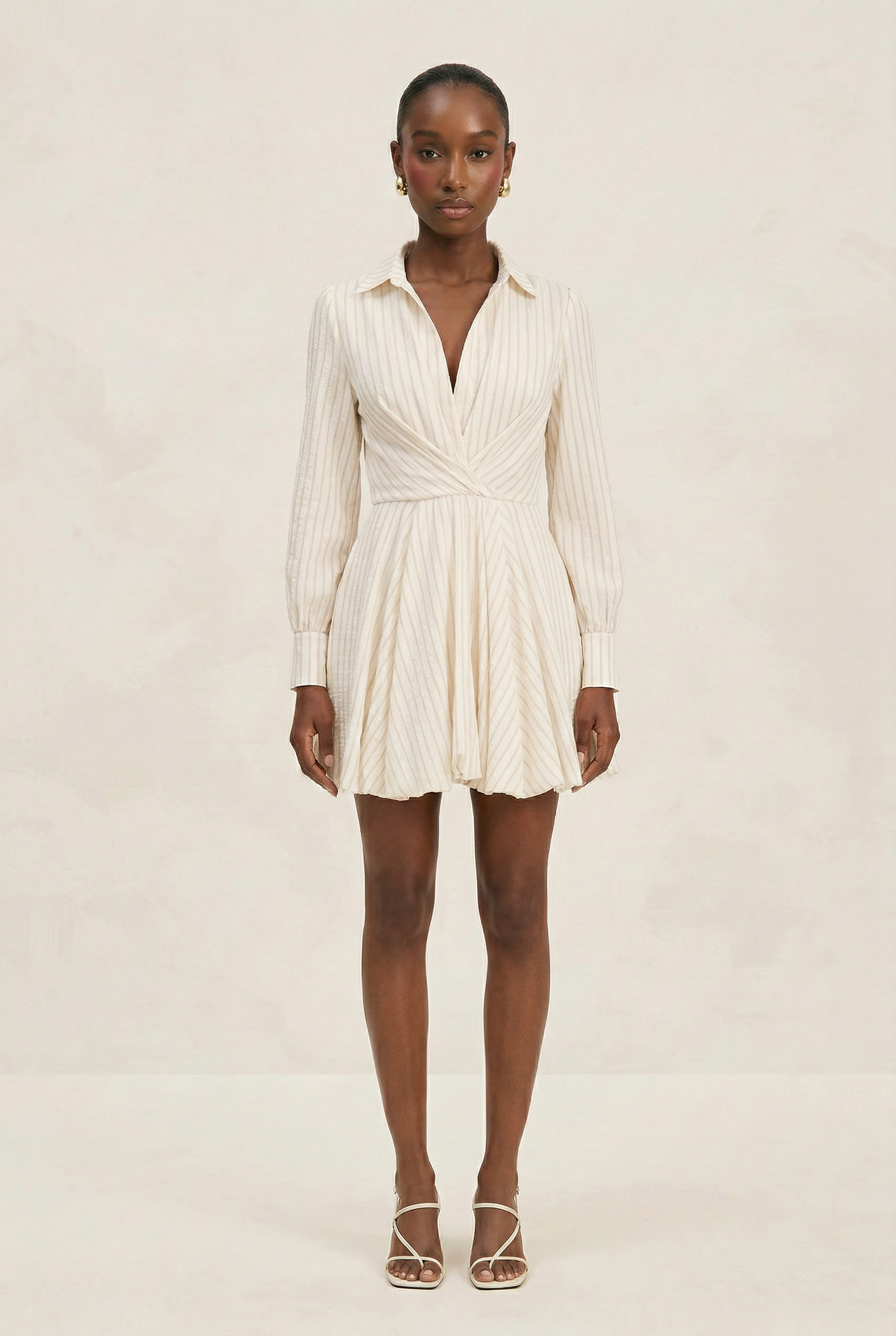 Woman wearing a white ribbed dress on a plain background