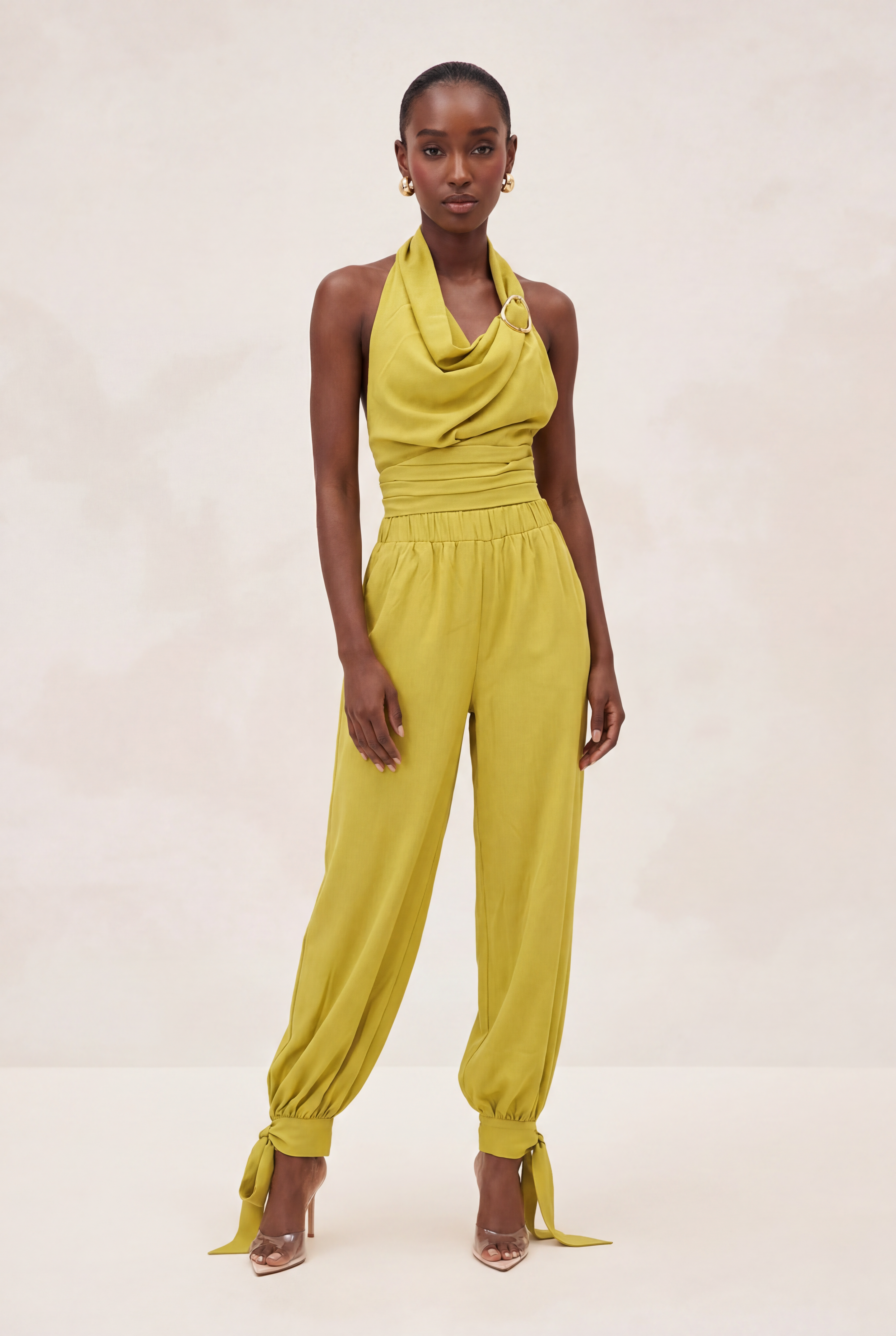 Woman wearing a yellow jumpsuit on a plain background