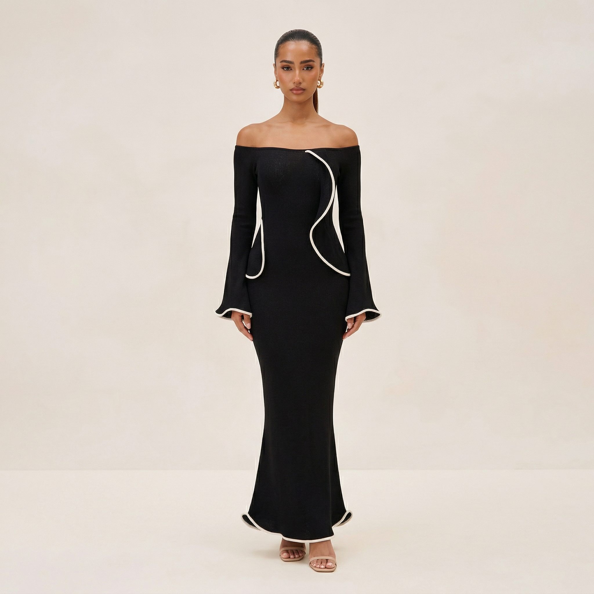 Woman wearing a black off-shoulder dress with white trim on a beige background