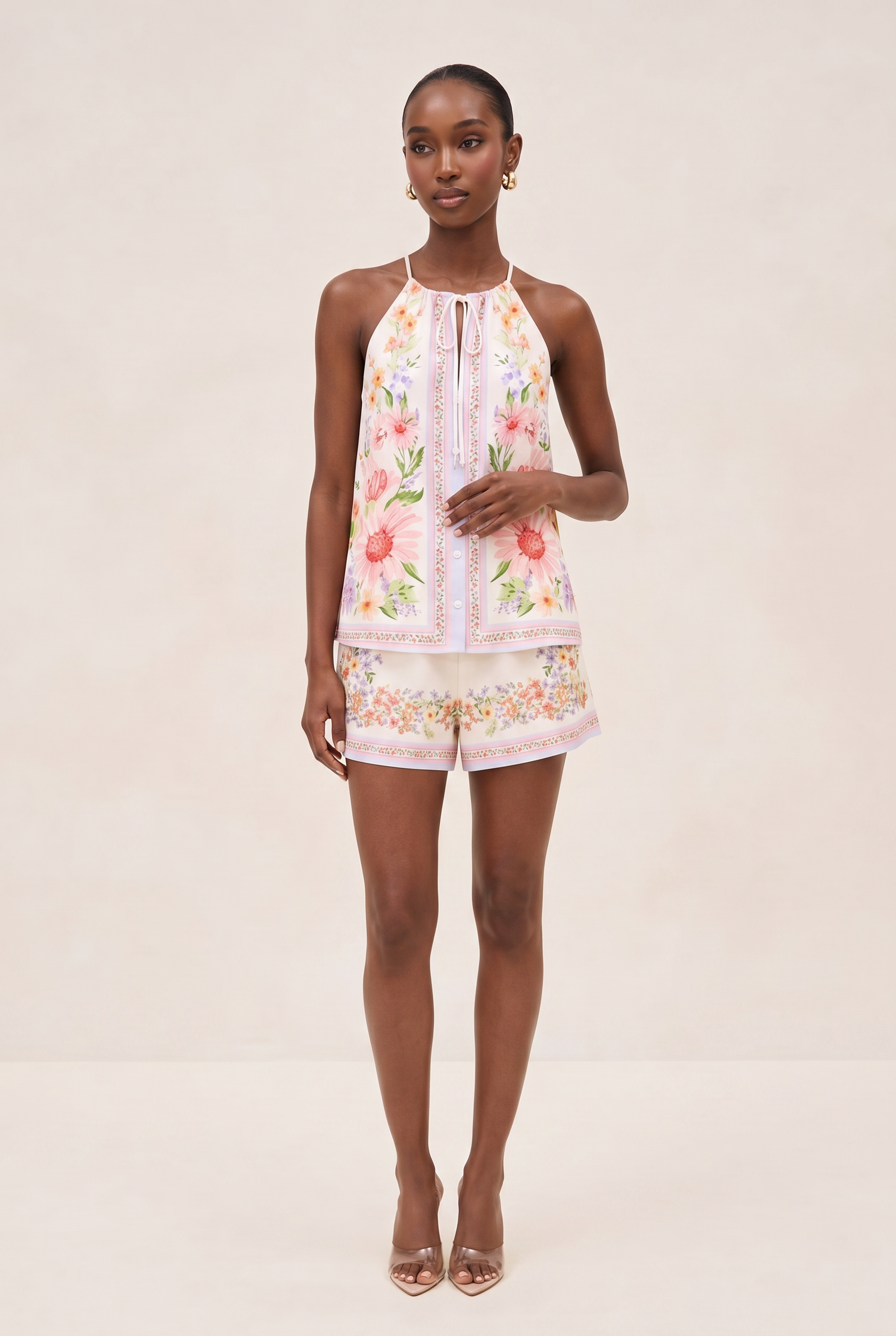 Woman wearing a floral dress and shorts on a plain background