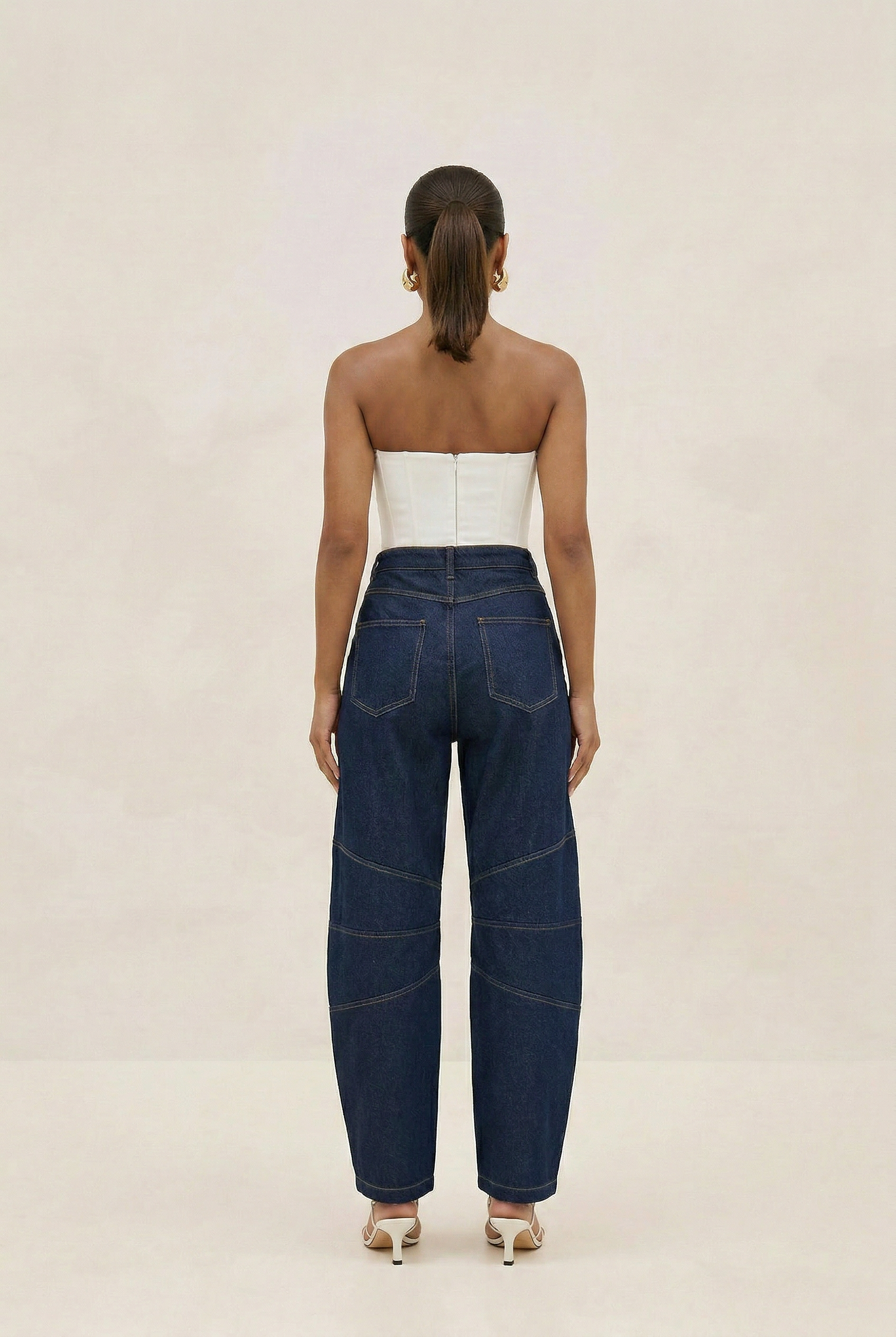 Woman wearing blue jeans and a white top on a beige background