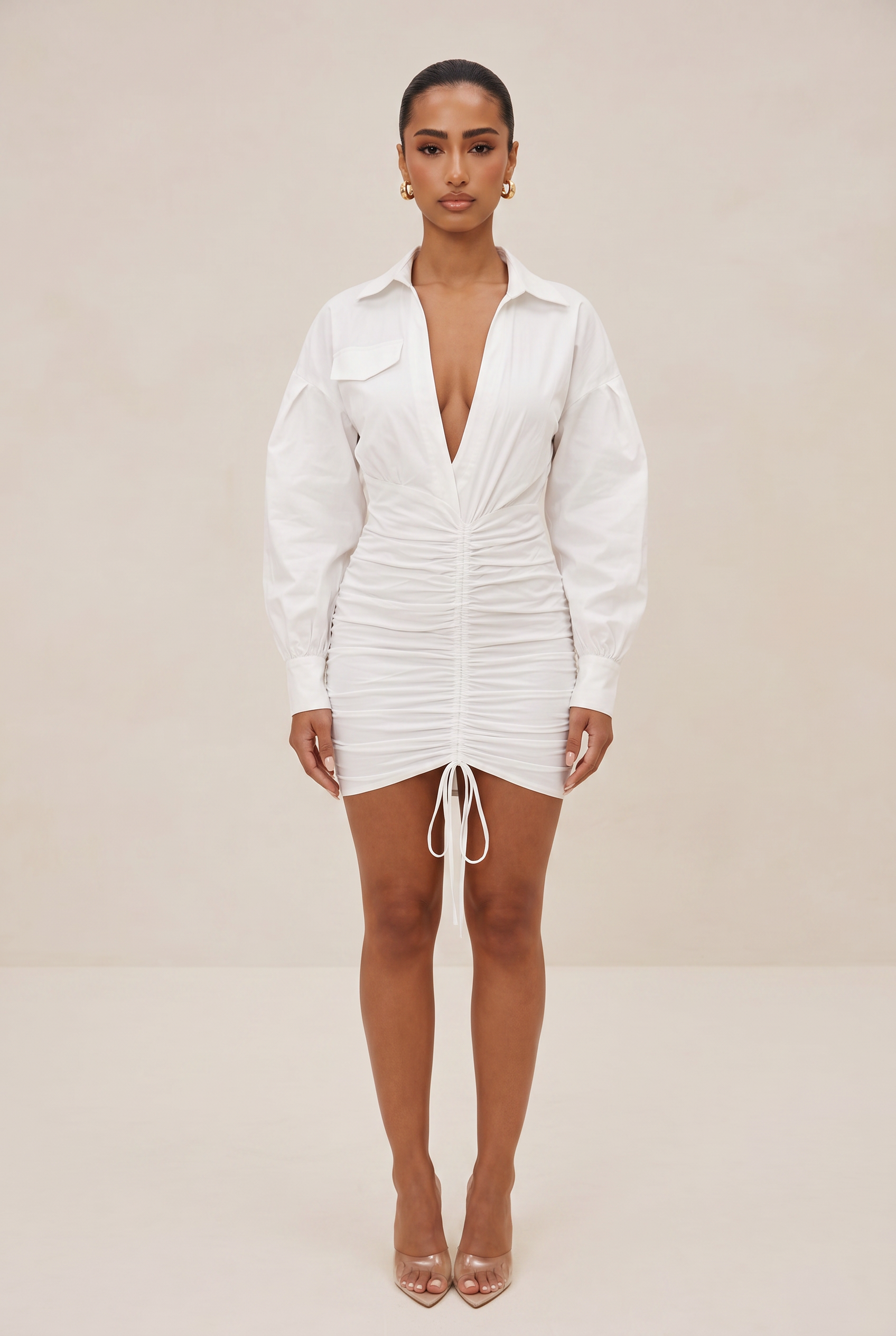 Woman wearing a white ruched dress against a beige background