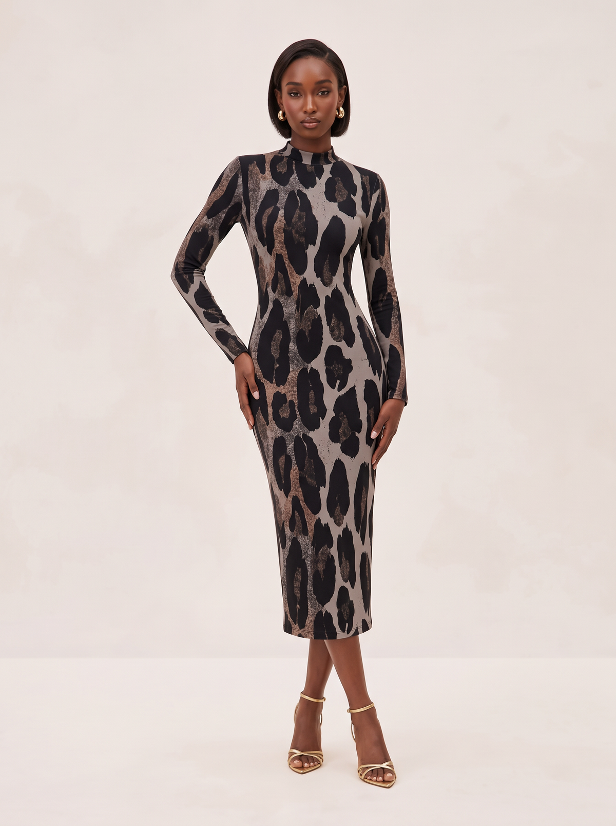 A woman modeling a long-sleeve, high-neck midi dress with a black and brown leopard print on a beige background, paired with gold high-heeled sandals, against a light beige studio backdrop.