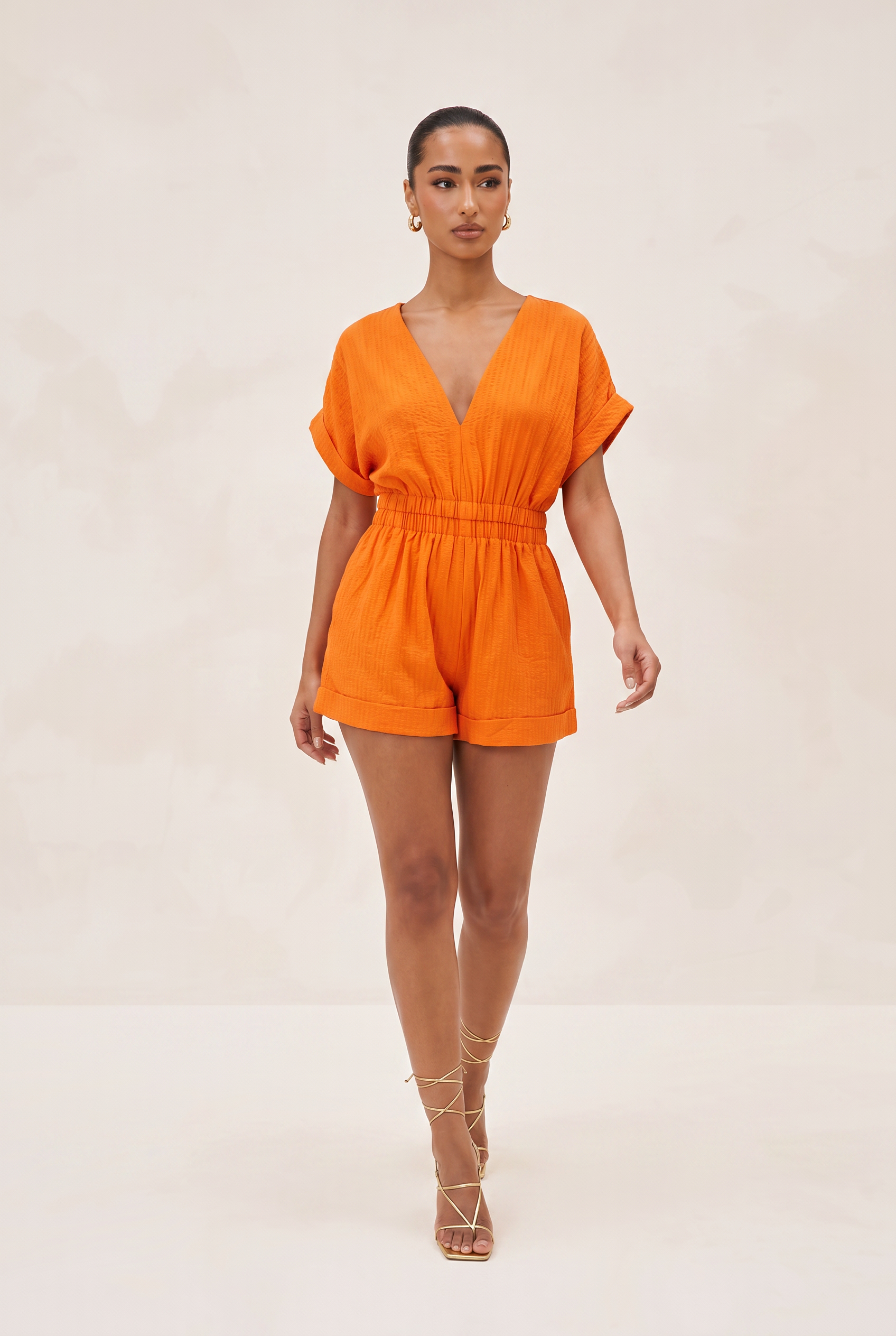 Woman wearing an orange jumpsuit on a plain background